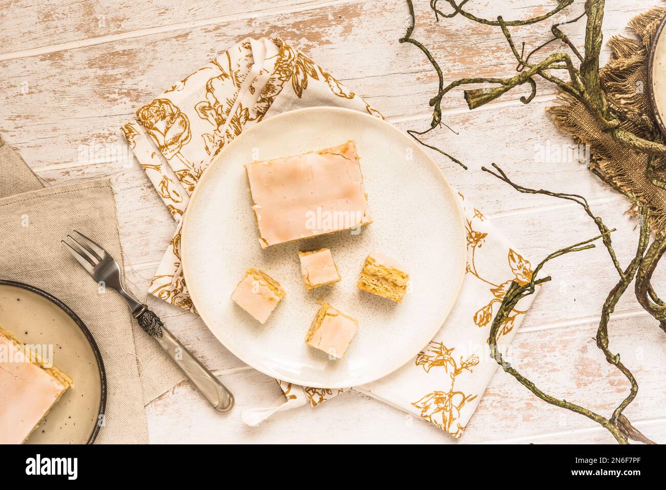 Assiette avec morceaux de tarte aux pommes couverte avec glaçage au sucre sur fond de bois blanc. Concept de couleur harmonieuse dans les tons beige. Vue de dessus. Banque D'Images