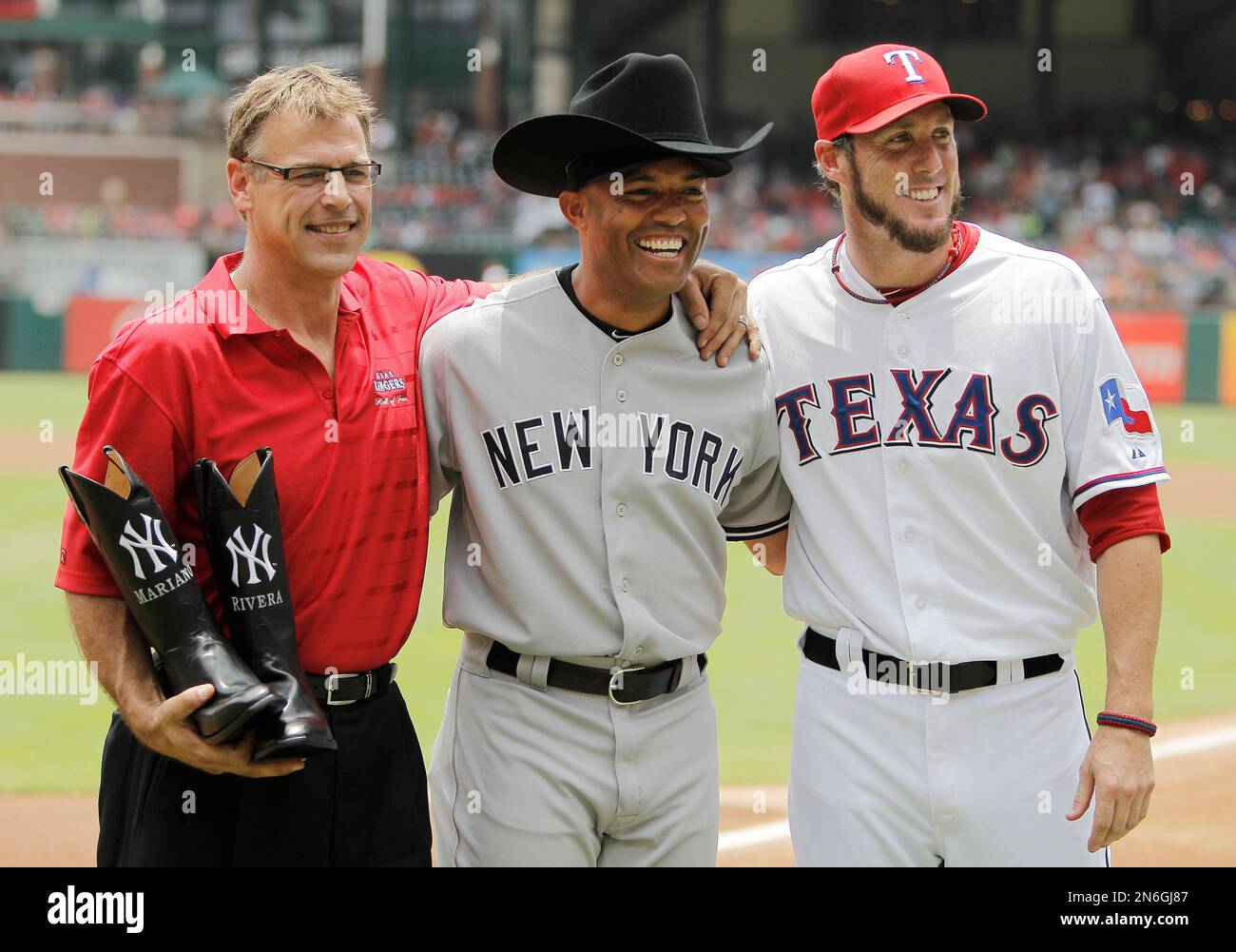 File-This July 25, 2013 file photo shows former Texas Rangers closer John Wetteland, left, and Rangers relief pitcher Joe Nathan, right, posing for a photo with New York Yankees relief pitcher Mariano Rivera, center, after presenting him with cowboy boots and hat before the start of the first inning of a baseball game in Arlington, Texas. (AP Photo/Brandon Wade, File) Banque D'Images