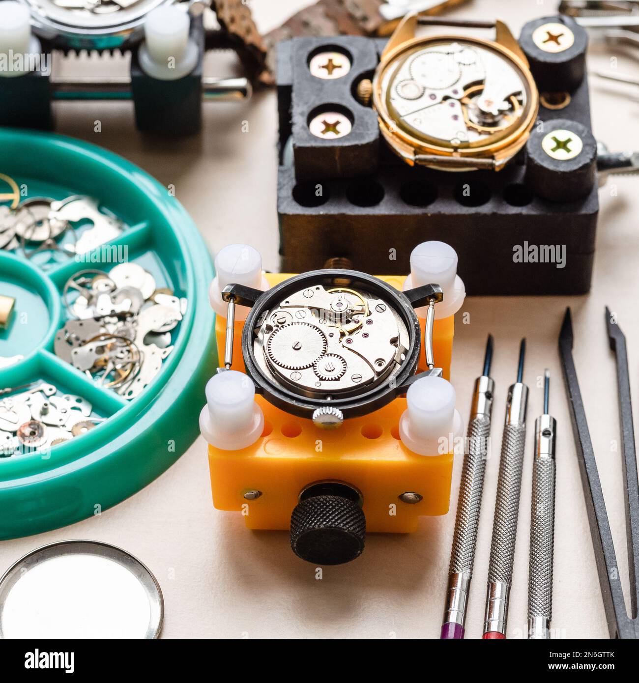 vieilles montres dans les supports et les outils sur une table en bois dans l'atelier horloger Banque D'Images