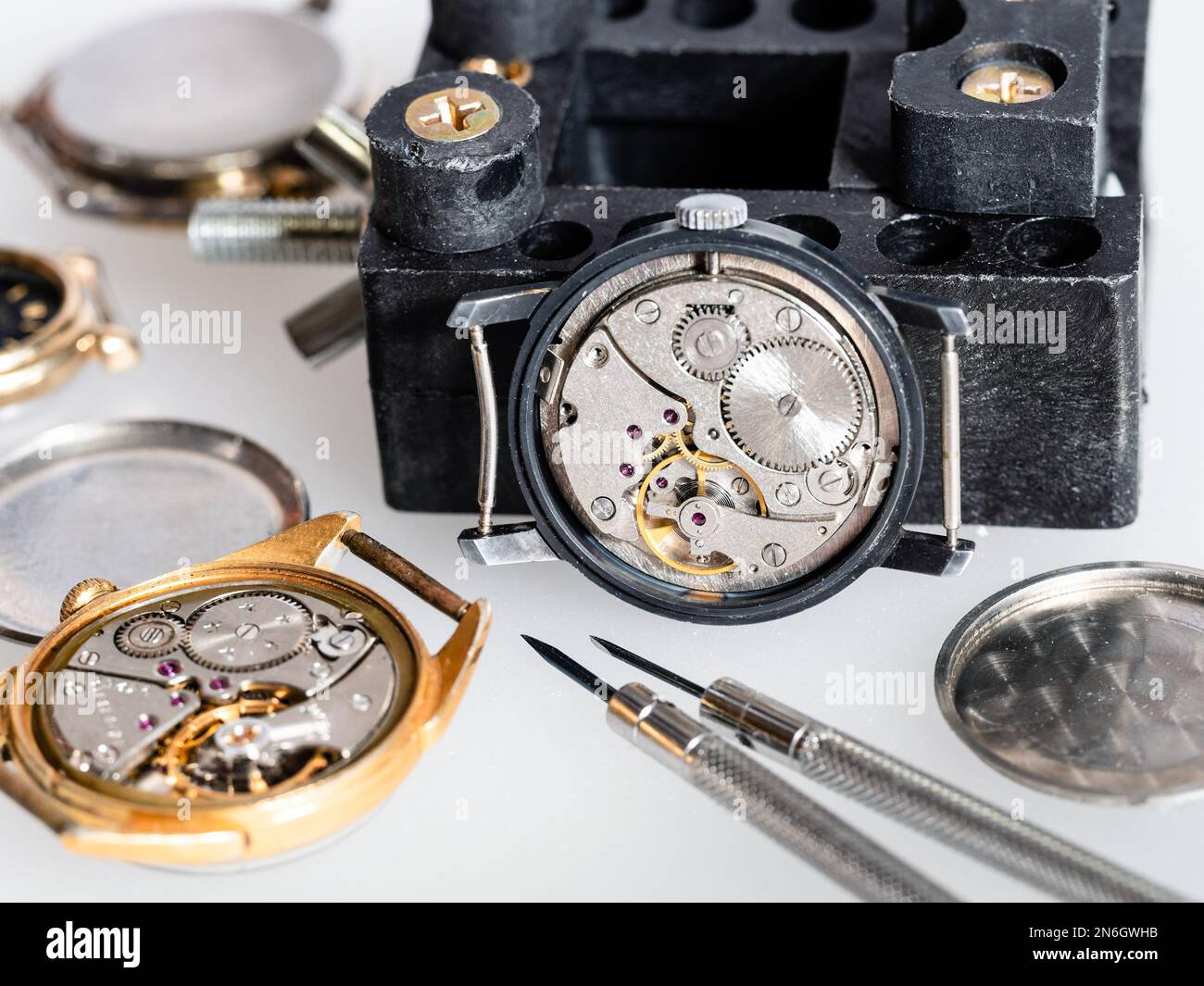 plusieurs vieilles montres mécaniques ouvertes et tournevis sur tableau blanc dans l'atelier horloger Banque D'Images