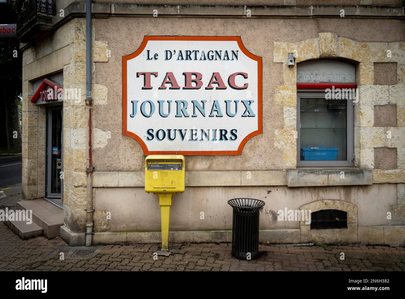 Panneau d'affichage sur le mur de la boutique le d'Artagnan avec boîte aux lettres et corbeille à papier en face de lui, vieille ville historique d'Auch, département Gers Banque D'Images