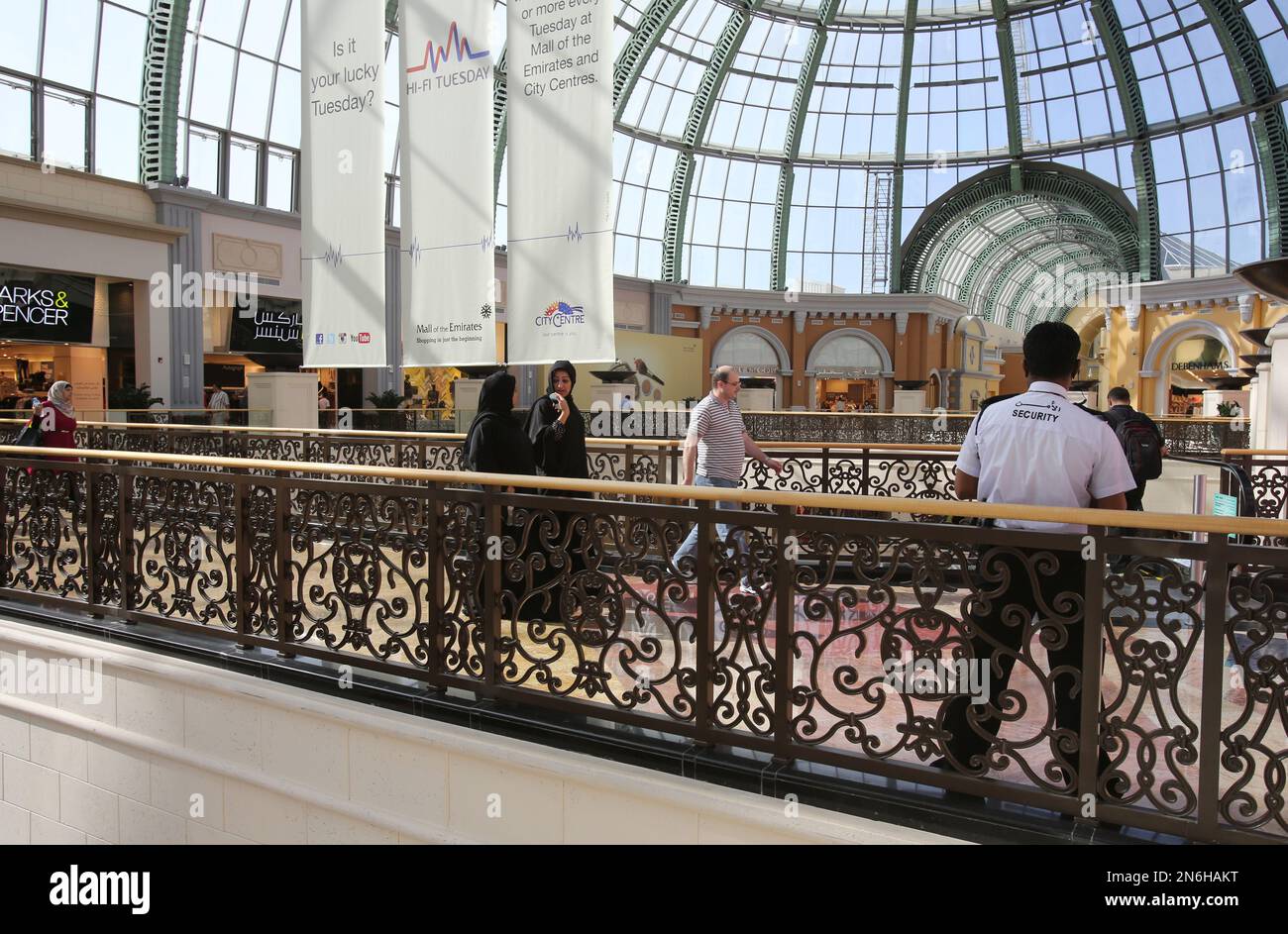 Visitors walk past a security guard stands on duty at a shopping mall in Dubai, United Arab Emirates on Wednesday, Sept. 25, 2013. The shopping mall industry continues to struggle with how to keep shoppers safe without scaring them away. (AP Photo/Kamran Jebreili) Banque D'Images