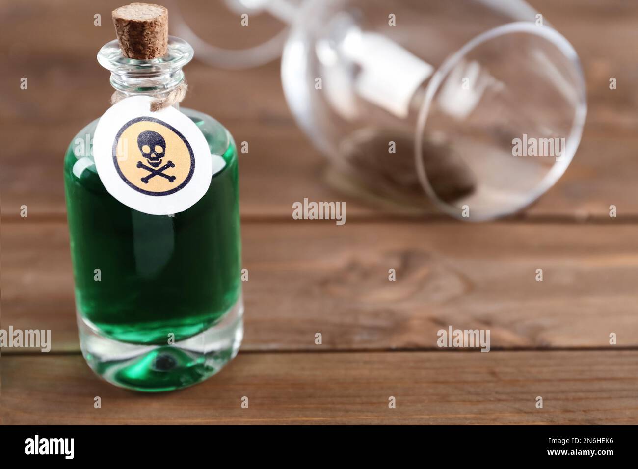 Bouteille de poison et verre partiellement vidé sur table en bois Banque D'Images