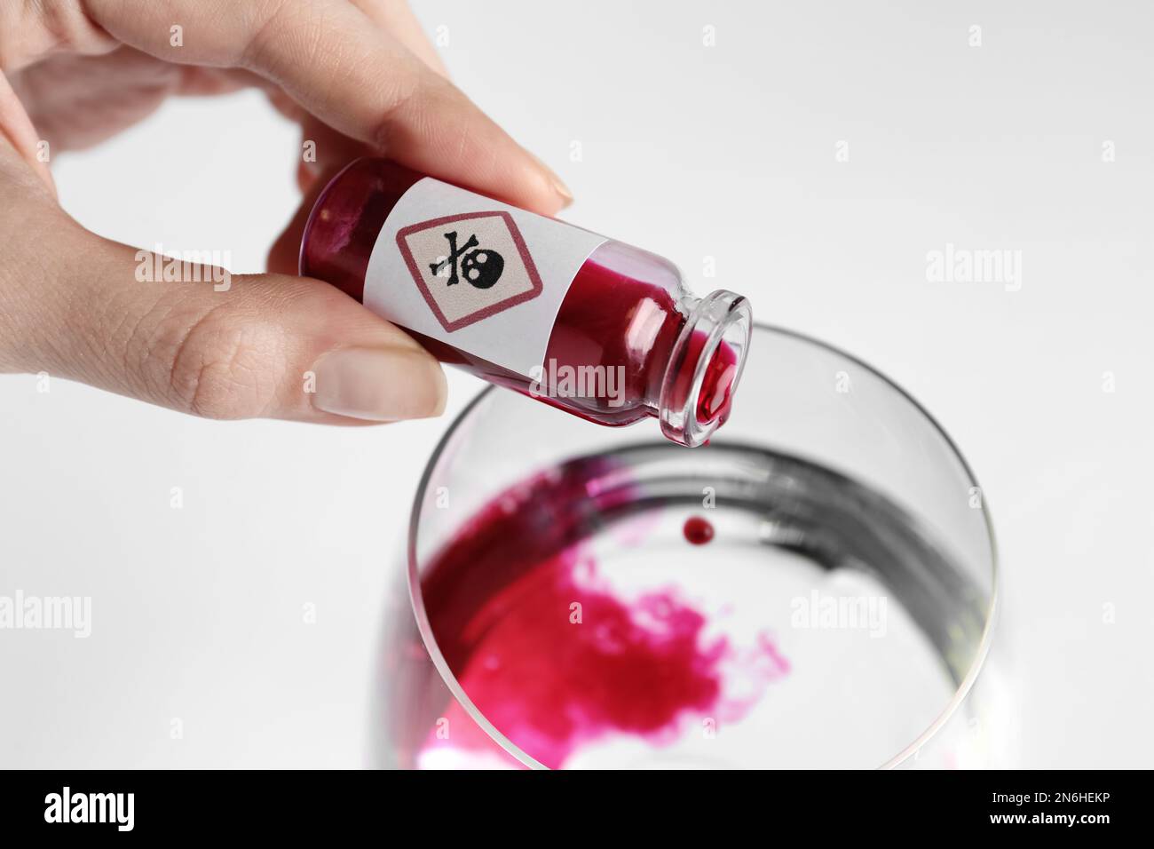 Femme versant du poison dans un verre d'eau sur fond blanc, gros plan Banque D'Images