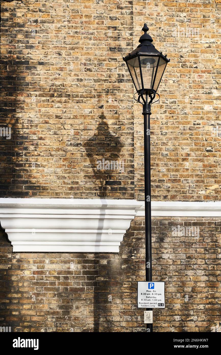 Vieille lampe de rue devant le mur jaune de clinker avec panneau de stationnement, Londres, Angleterre, Grande-Bretagne Banque D'Images
