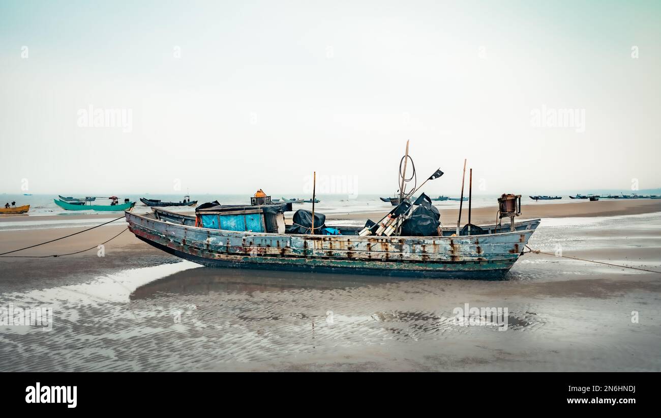 Un bateau de pêche traditionnel en bois se trouve coincé à marée basse sur la plage de Tra Co, à la frontière avec la Chine près de Mong Cai, au Vietnam. Banque D'Images