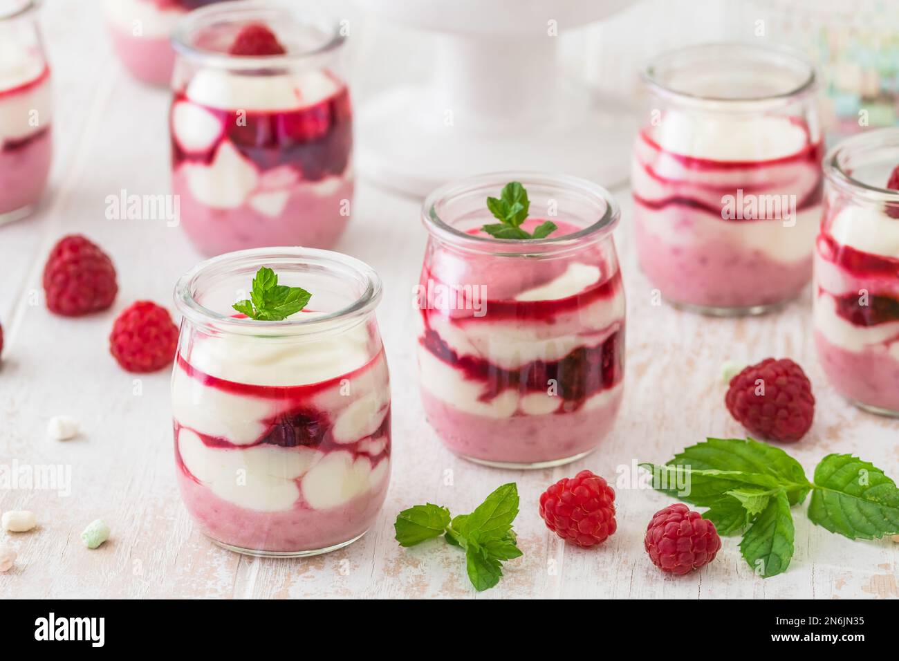 Dessert fruité au fromage blanc avec framboises et chocolat ou garniture croustillante dans de petits verres Banque D'Images