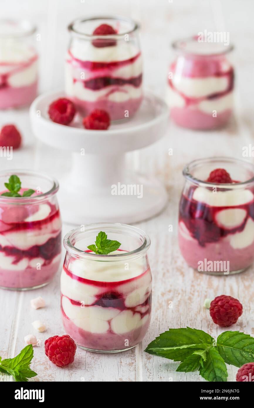 Dessert fruité au fromage blanc avec framboises et chocolat ou garniture croustillante dans de petits verres Banque D'Images