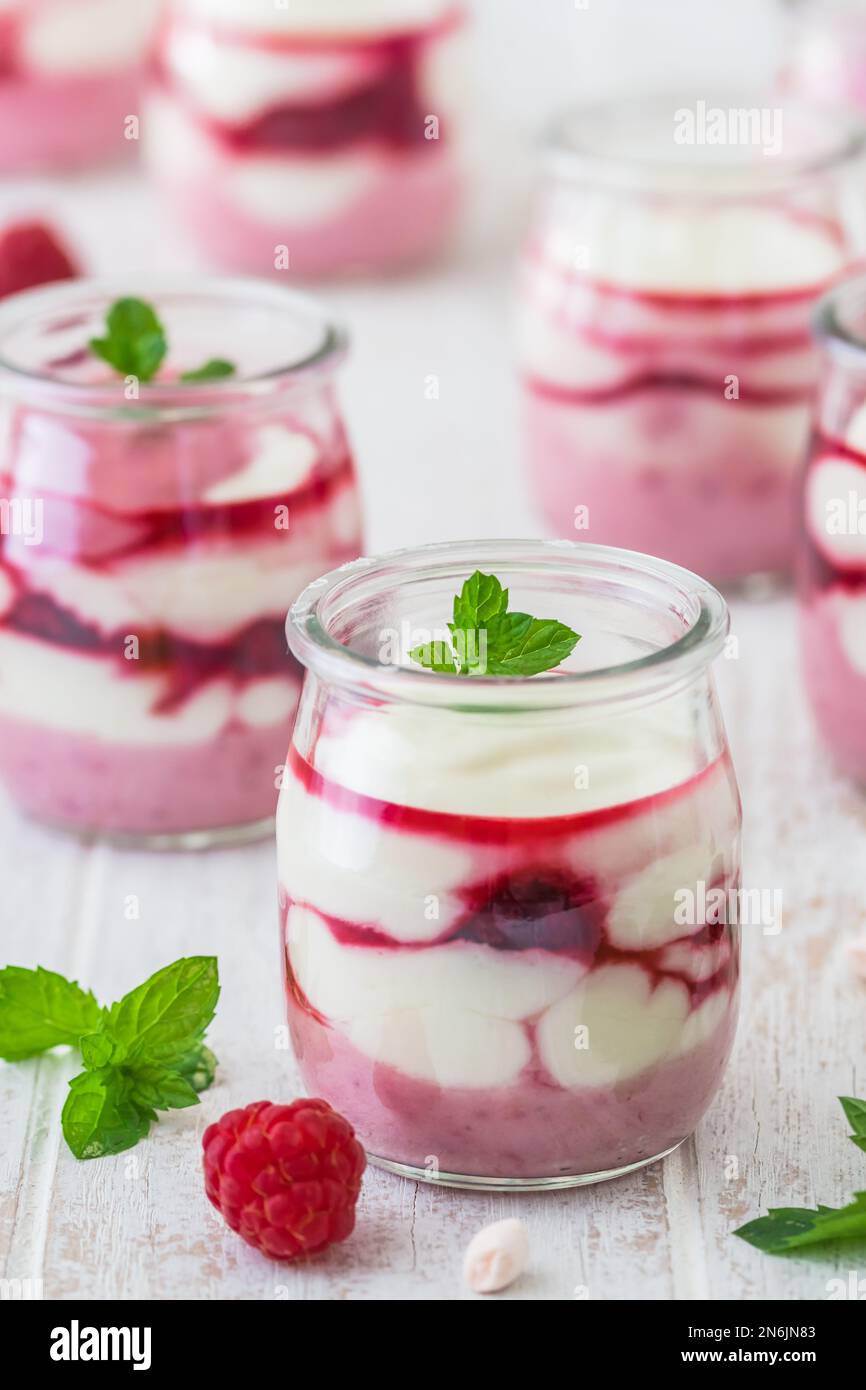 Dessert fruité au fromage blanc avec framboises et chocolat ou garniture croustillante dans de petits verres Banque D'Images