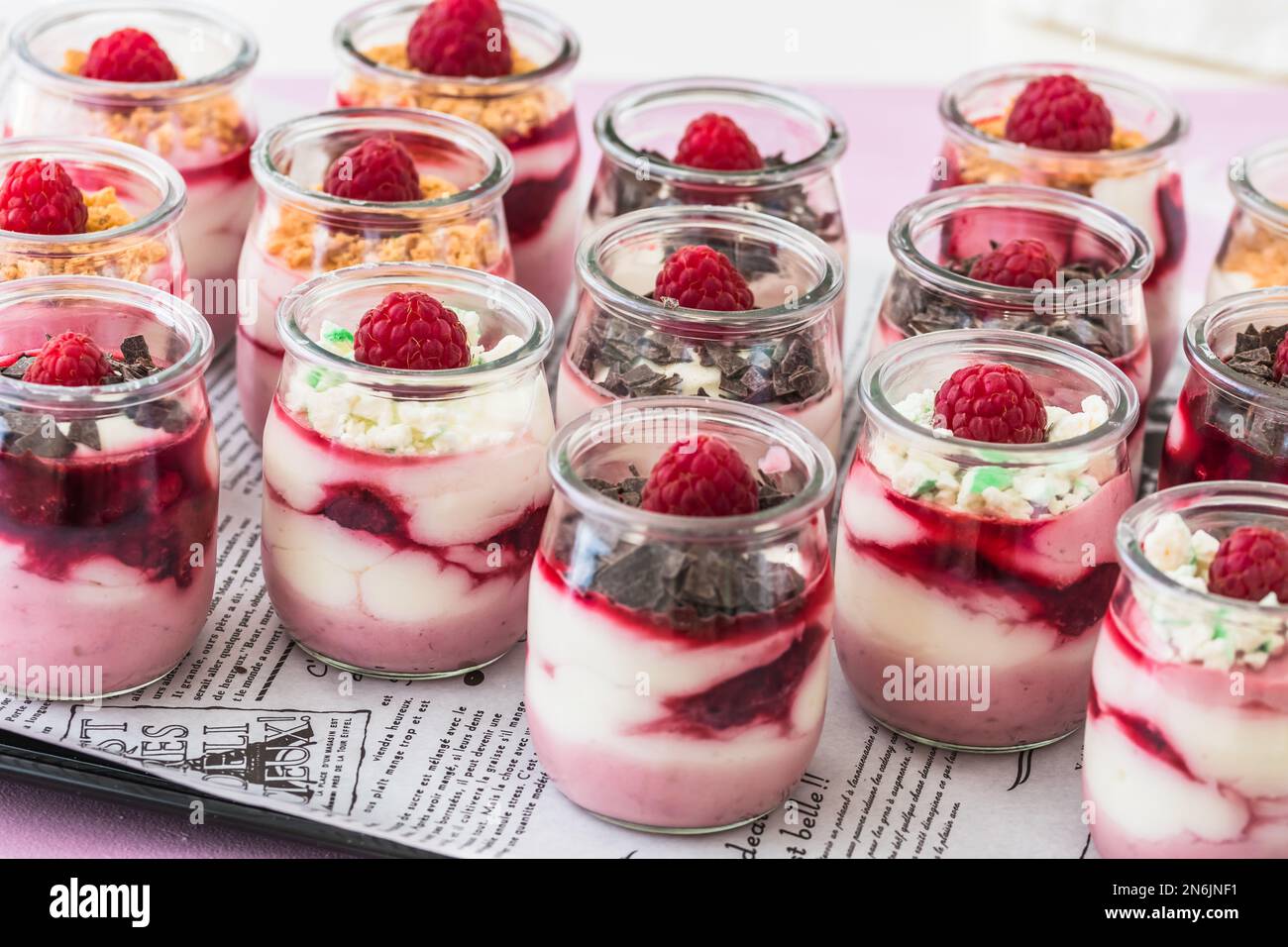 Dessert fruité au fromage blanc avec framboises et chocolat ou garniture croustillante dans de petits verres Banque D'Images
