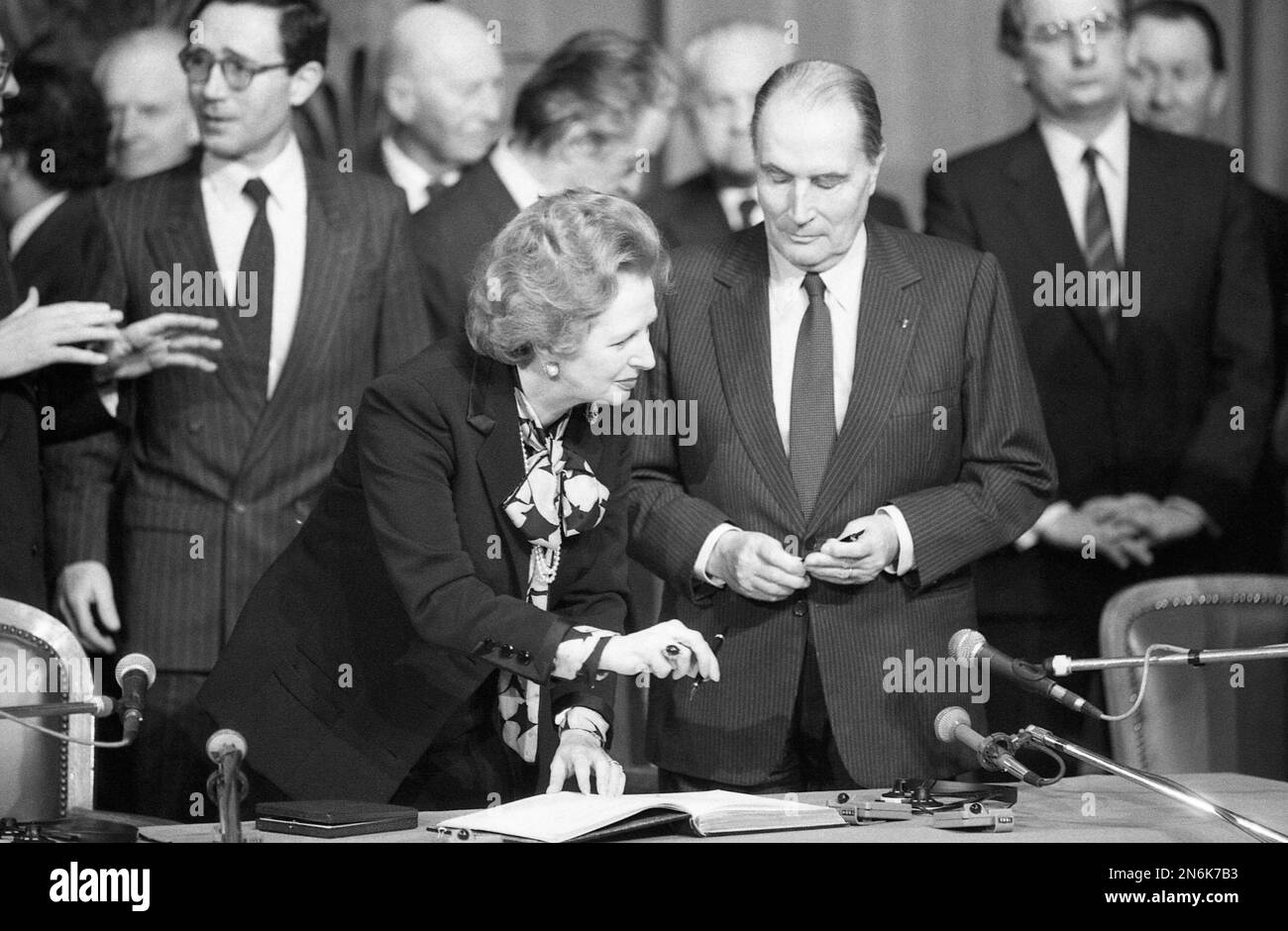 Britain's Prime Minister Margaret Thatcher passes her pen to French