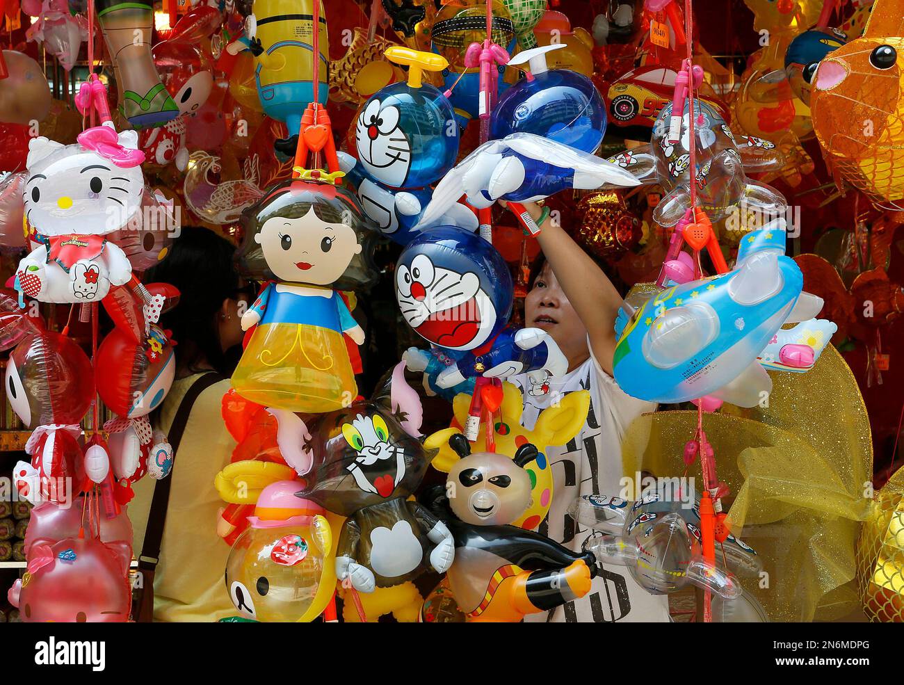 A woman selects a cartoon character-shaped lantern at a shop for the upcoming Chinese Mid-Autumn Festival in Hong Kong Sunday, Sept. 15, 2013. People in Hong Kong prepare to celebrate the festival, which falls on Thursday Sept. 19 this year. Chinese people believe that on the day, the moon will be the biggest, roundest and brightest, and the term "round" implies family reunion in Chinese. (AP Photo/Vincent Yu) Banque D'Images
