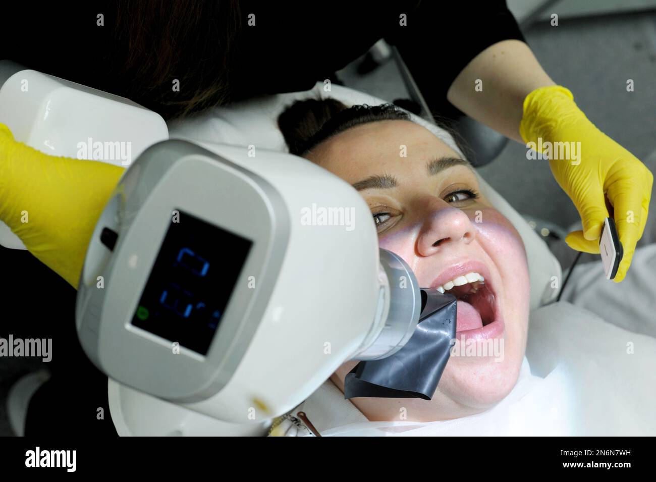 la dernière technologie en clinique dentaire avec l'aide de la nouvelle femme scanner à rayons x est prise photo canaux remplissant la femme sourit jolie médecin jaune gants an Banque D'Images