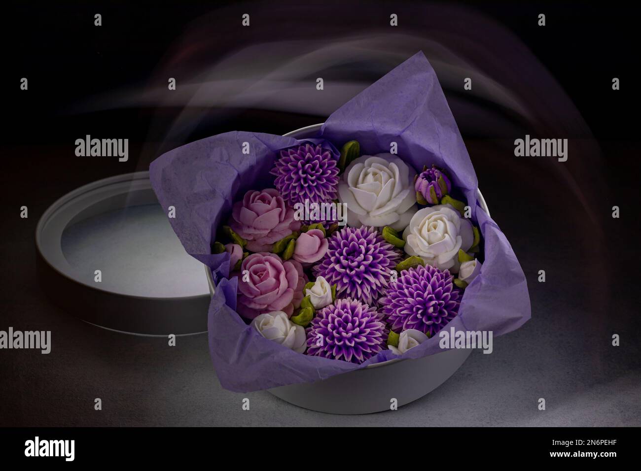 Bouquet de fleurs de guimauve dans une boîte cadeau sur fond sombre, avec un pinceau clair. Banque D'Images