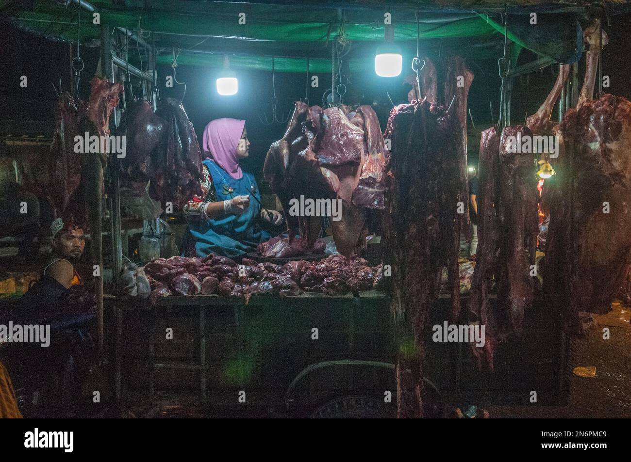 Une femme musulmane qui vend de la viande crue au principal marché de gros de légumes et de viande, Phsar Dumkor, la nuit à Phnom Penh, au Cambodge. © Kraig Lieb Banque D'Images