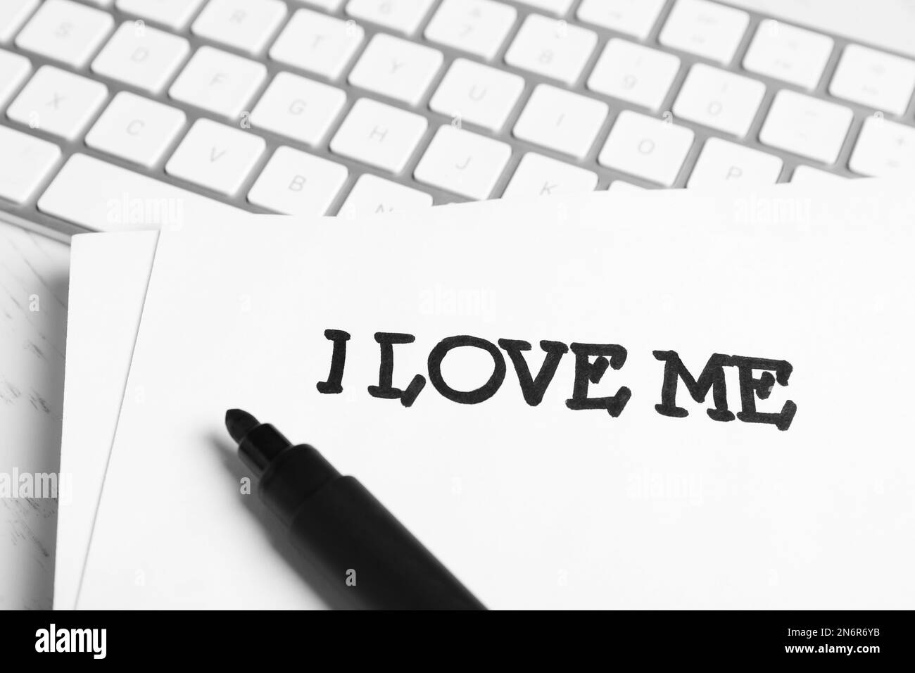 Papier avec la phrase manuscrite I Love Me et clavier d'ordinateur sur le bureau, gros plan Banque D'Images