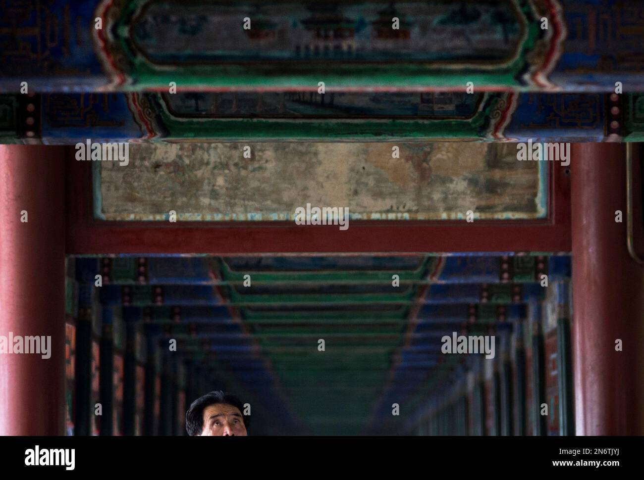 A man looks up as he walks along the Long Corridor, known as the "Chang Lang" display with thousand of colorful paintings depicting landscapes, birds and flowers from Chinese literary classics, at the Summer Palace in Beijing Wednesday, Aug. 28, 2013. The Summer Palace, which was the retreat once used by China's Qing Dynasty emperors to escape the city heat, is a popular tourist destination in the capital city. (AP Photo/Andy Wong) Banque D'Images