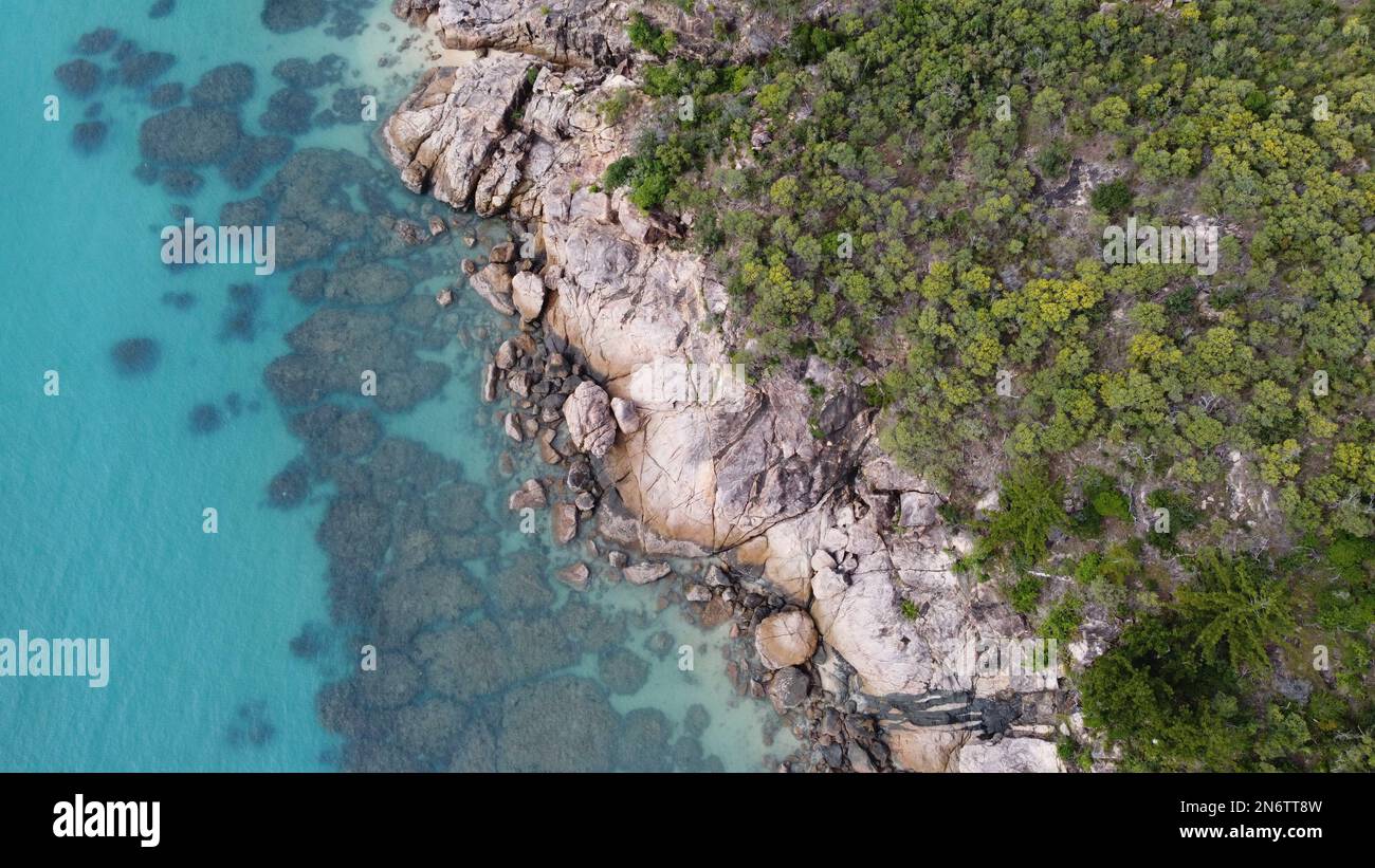 Image aérienne abstraite de l'eau claire et du récif contre une rive rocheuse avec des palmiers Banque D'Images