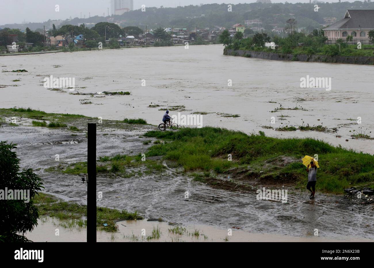 Residents look at the swollen Marikina River as flooding reaches critical levels Marikina city, east of Manila, Philippines, Tuesday, Aug. 20, 2013. Flooding caused by some of the Philippines' heaviest rains that submerged more than half the capital began receding Tuesday, but authorities evacuated thousands of residents along Manila's overflowing rivers and braced for more chaos in outlying provinces. (AP Photo/Bullit Marquez) Banque D'Images