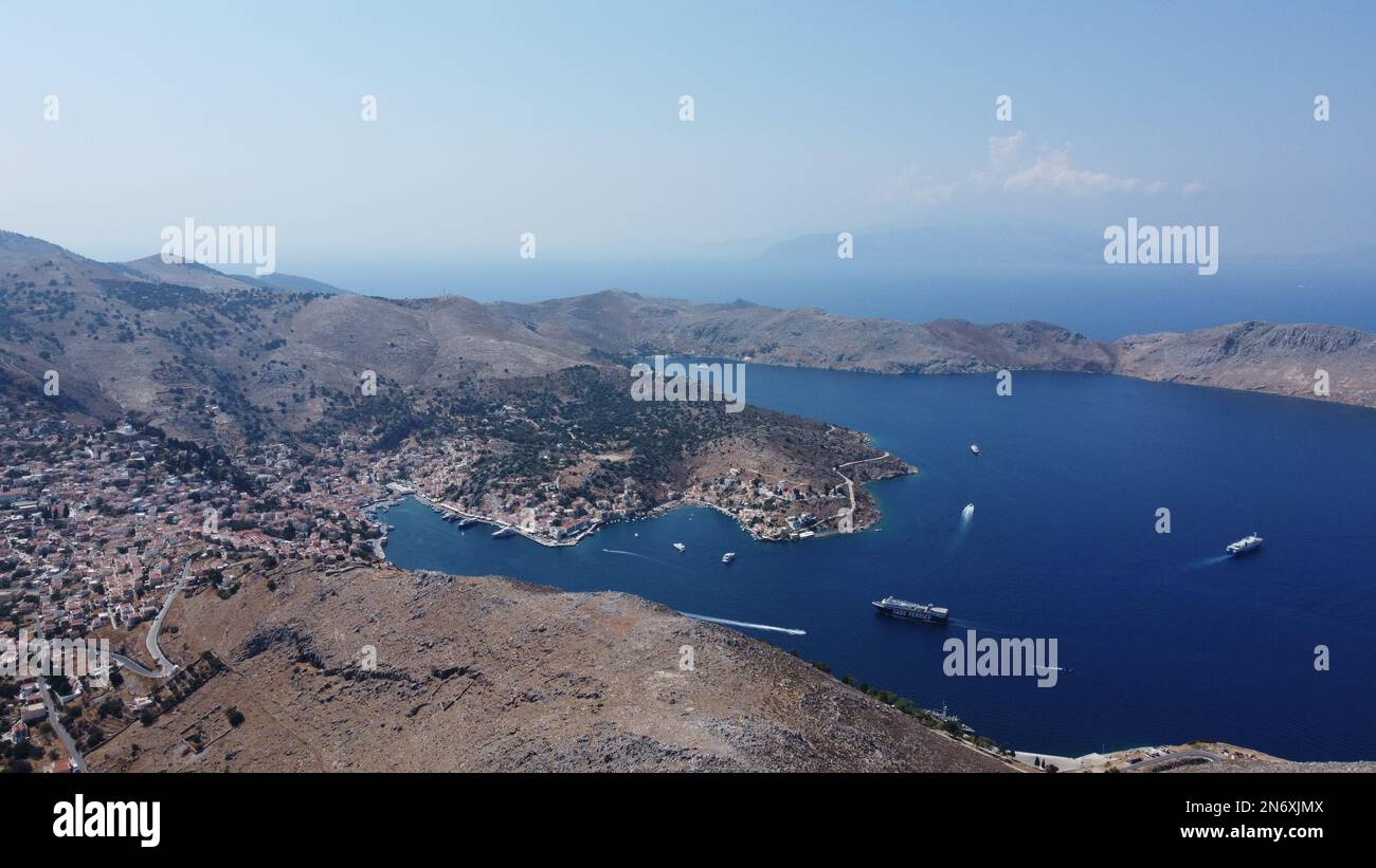 Prise de vue aérienne du port principal de Symi avec des bateaux entrant et sortant. Vous pouvez voir la Turquie en arrière-plan Banque D'Images