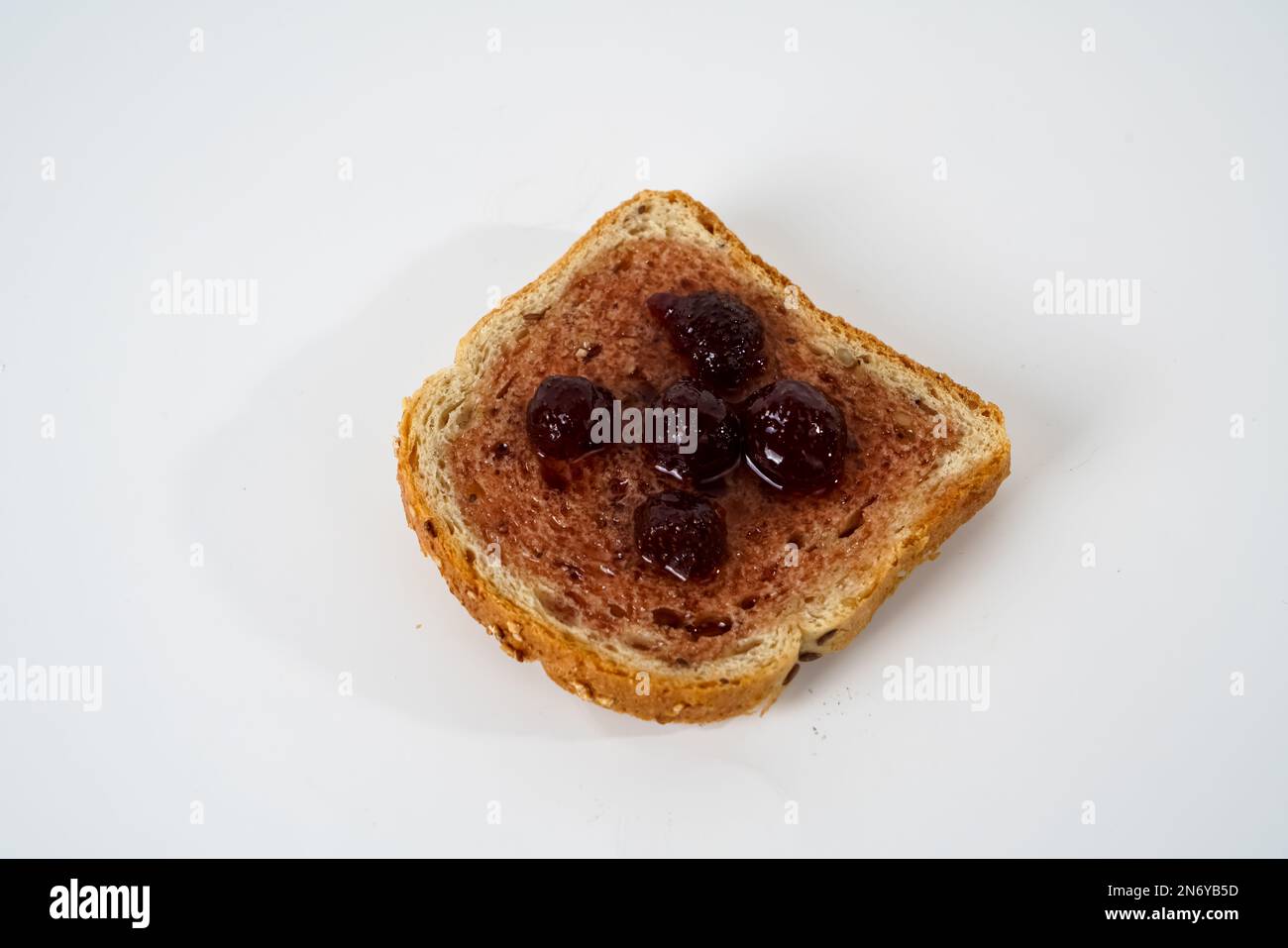Une tranche de pain avec confiture de fraise isolée sur fond blanc. Banque D'Images