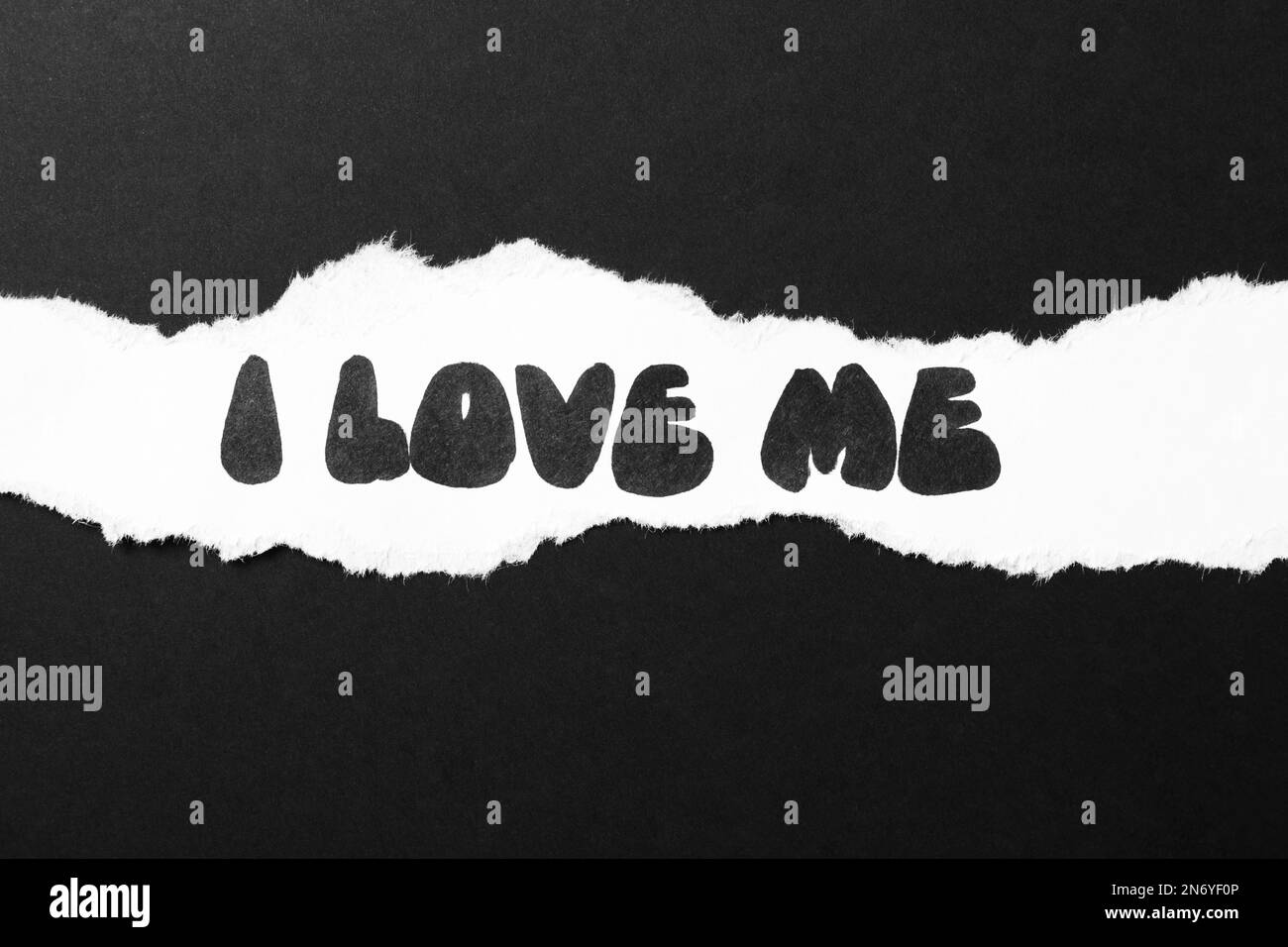Morceau de livre blanc avec la phrase I Love Me sur fond noir, vue de dessus Banque D'Images
