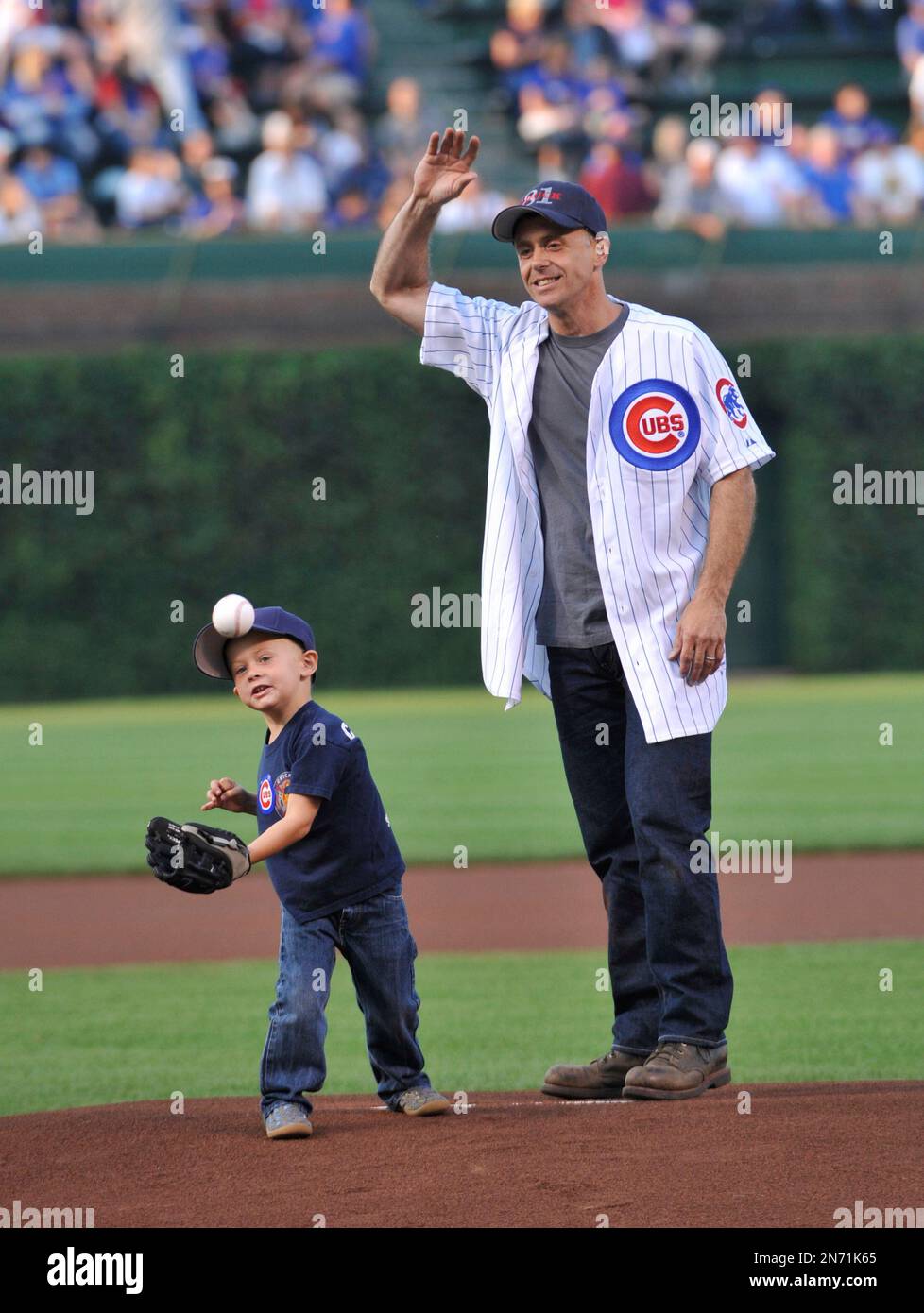 Actor David Eigenberg, from the television series "Chicago Fire," and his Louie throw out the ceremonial first pitch before a baseball game between the Chicago Cubs and the Milwaukee Brewers, Wednesday, July 31, 2013, in Chicago. (AP Photo/David Banks) Banque D'Images