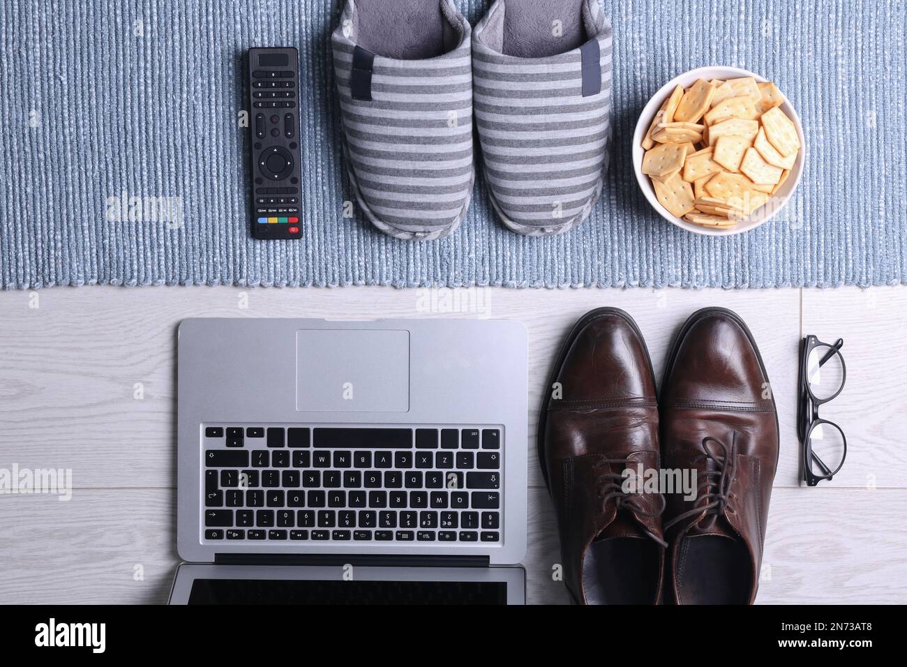 Composition de pose plate avec articles d'affaires et accessoires de maison sur plancher en bois avec tapis bleu. Concept d'équilibre entre travail et vie Banque D'Images