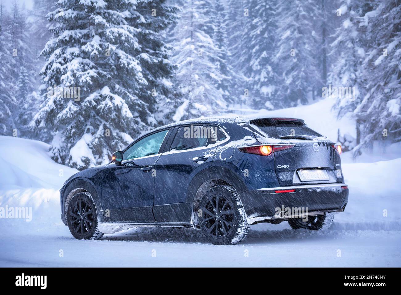 Italie, Vénétie, Belluno, une Mazda Motor Corp Véhicule utilitaire sport multisegment CX-30 (SUV) sur une route de montagne en hiver lors d'une chute de neige, les Dolomites Banque D'Images