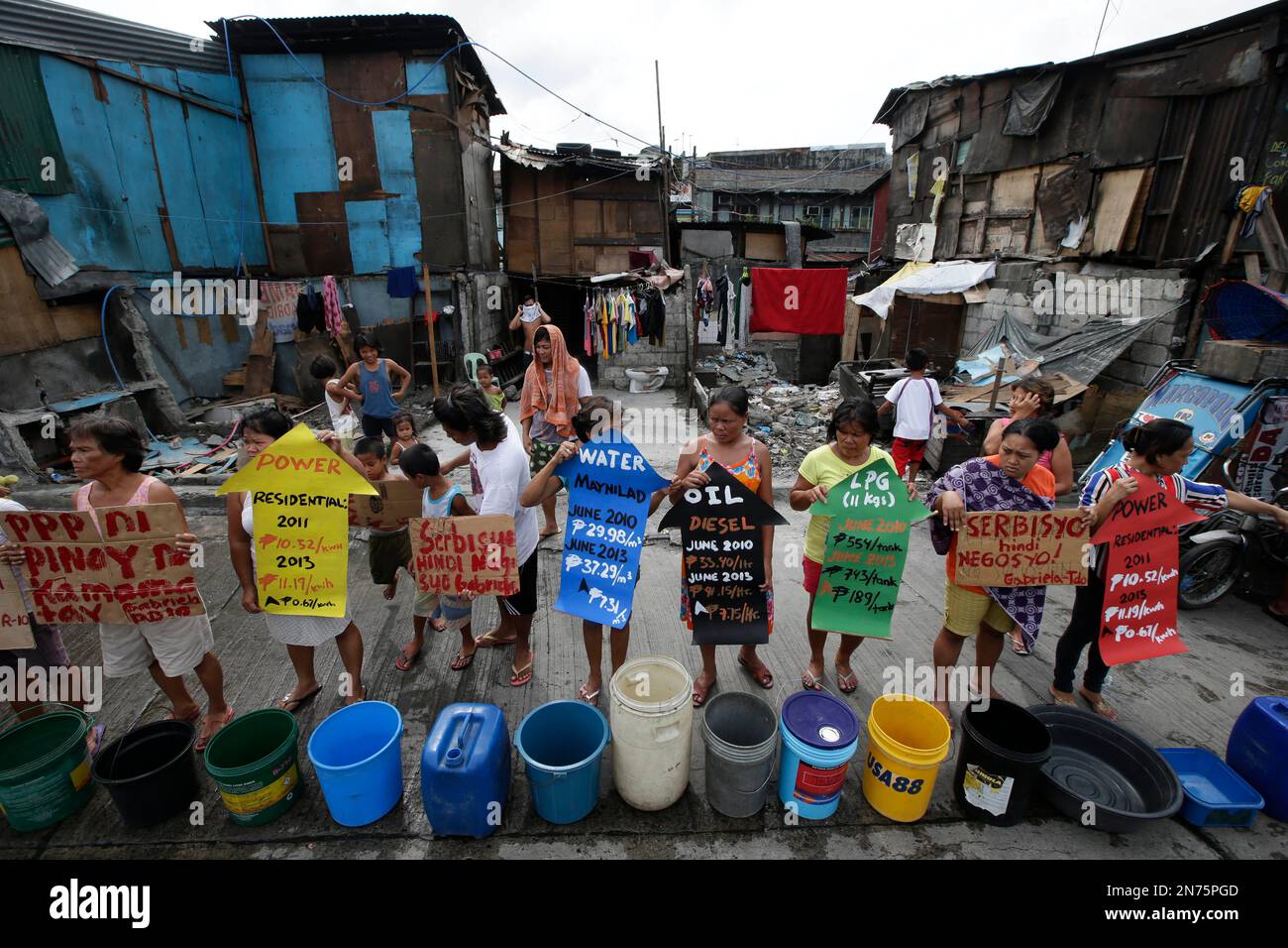 Residents living at a poor Manila district of Tondo line up empty plastic pails and containers to protest and urge Philippine President Benigno Aquino III to immediately order two big water concessionaires in the metropolis to refund alleged exorbitant and onerous pass-on charges to millions of Filipino consumers Friday, July 12, 2013. The pass-on charges were discovered following plans by the concessionaires to raise the water rates. (AP Photo/Bullit Marquez) Banque D'Images
