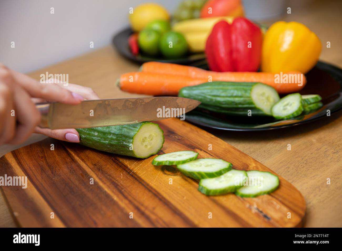 les mains des femmes trancheuses un concombre sur une planche à découper en bois Banque D'Images