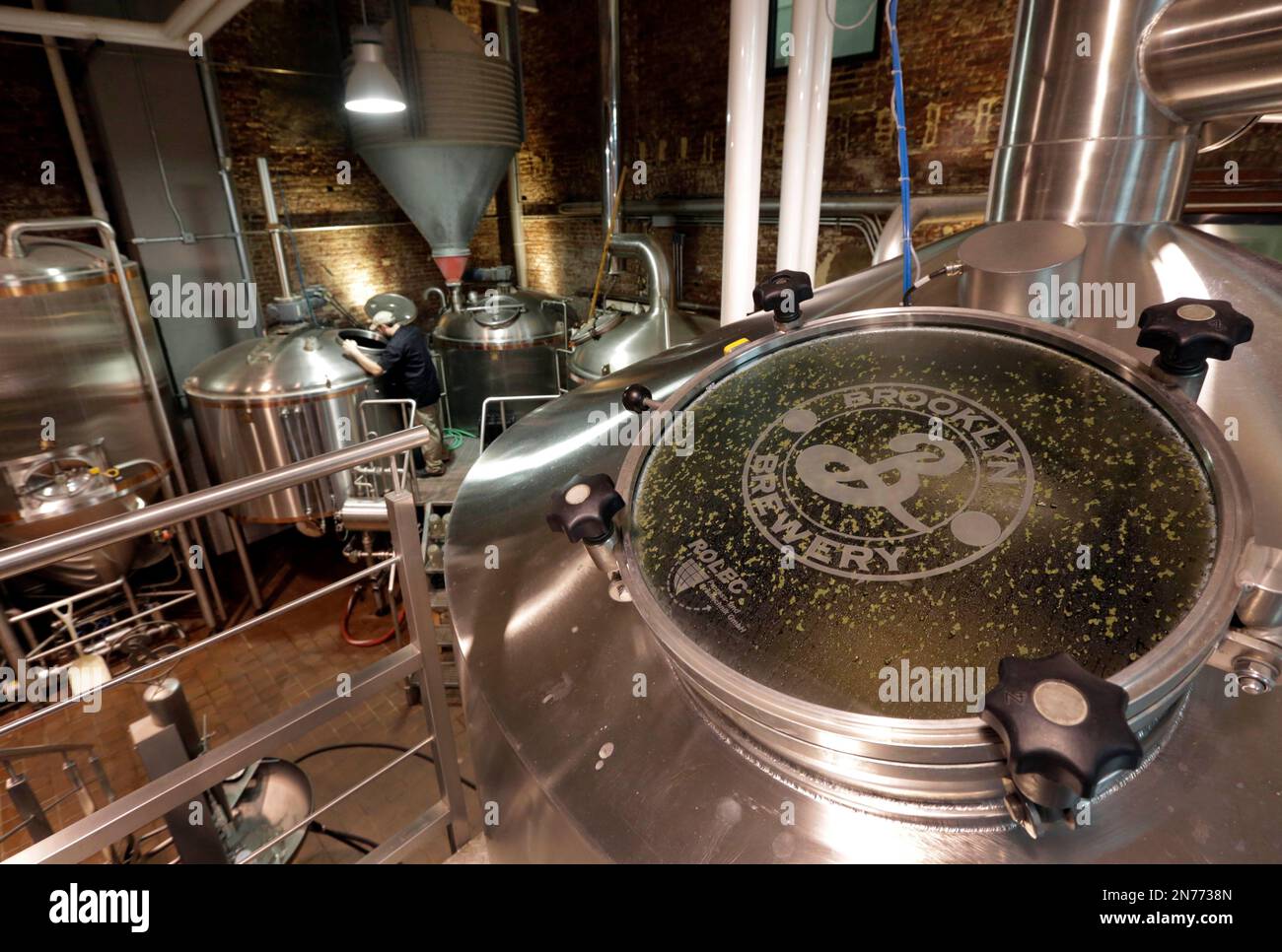 In this July 1, 2013 photo, Production Manager James Valm looks into Lauter Tun in the brew house of the Brooklyn Brewery, in the Williamsburg section of the Brooklyn borough of New York. In rundown urban neighborhoods across the country, craft breweries helped transform the neighborhoods around them, drawing young new residents and other small businesses. (AP Photo/Richard Drew) Banque D'Images