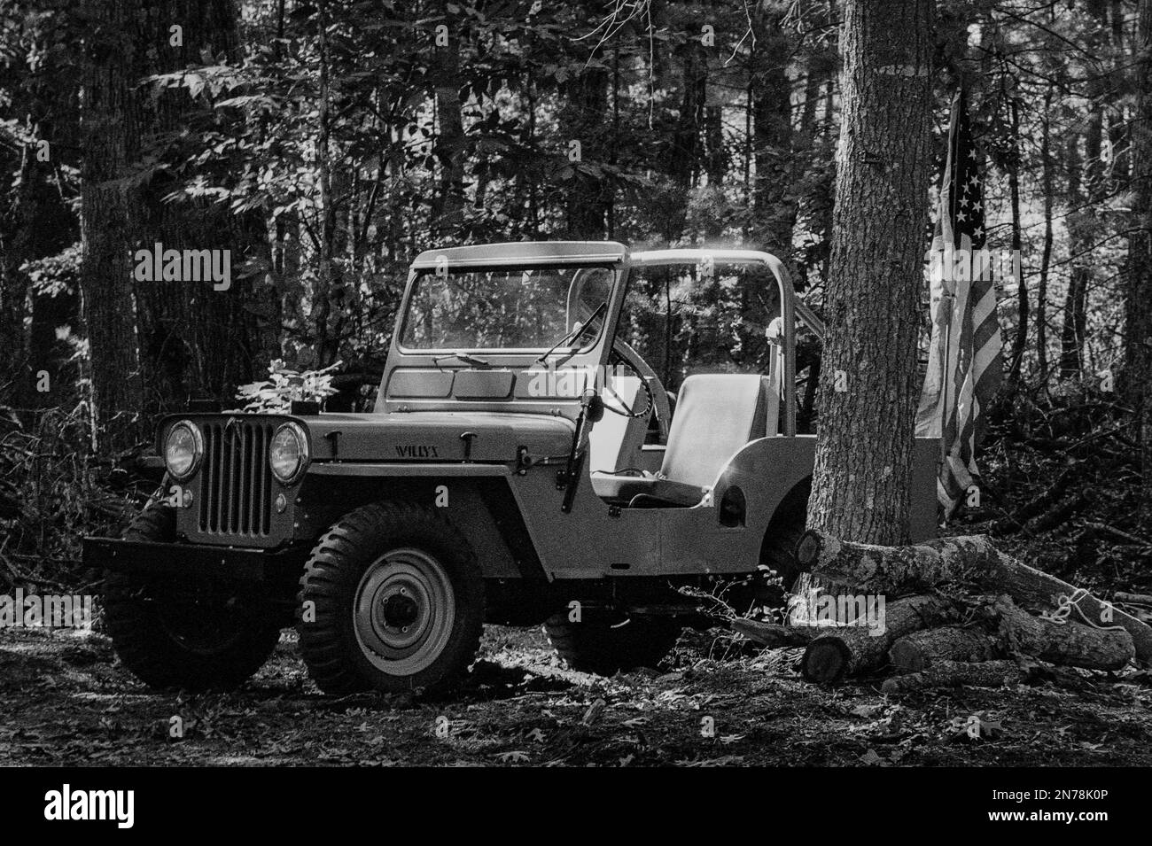 Une jeep Willys garée dans les bois avec un drapeau américain derrière elle pendant une reconstitution de la Seconde Guerre mondiale au Musée du patrimoine américain. L'image a été capturée sur Banque D'Images