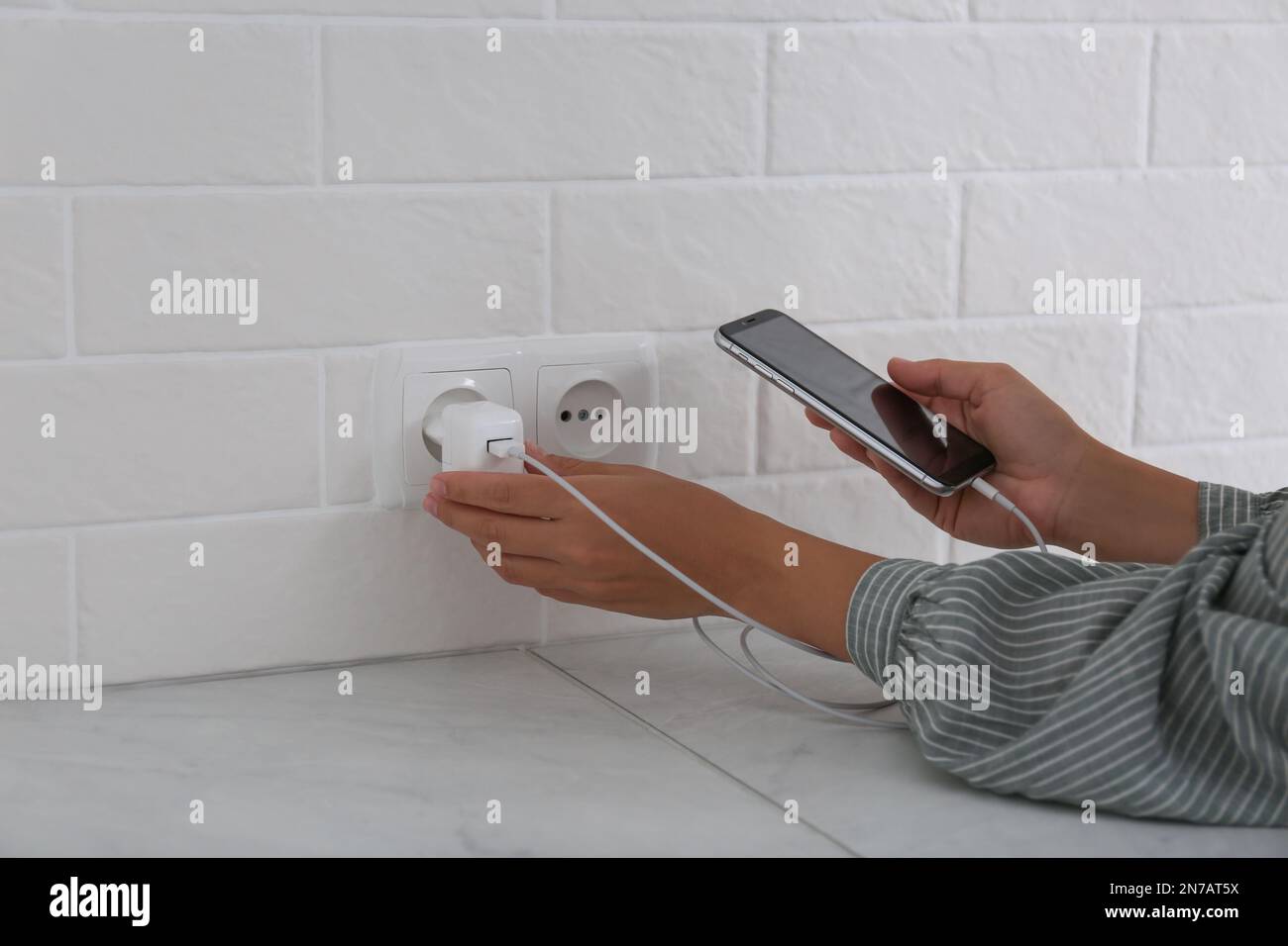 Femme avec téléphone portable brancher le chargeur dans la prise murale