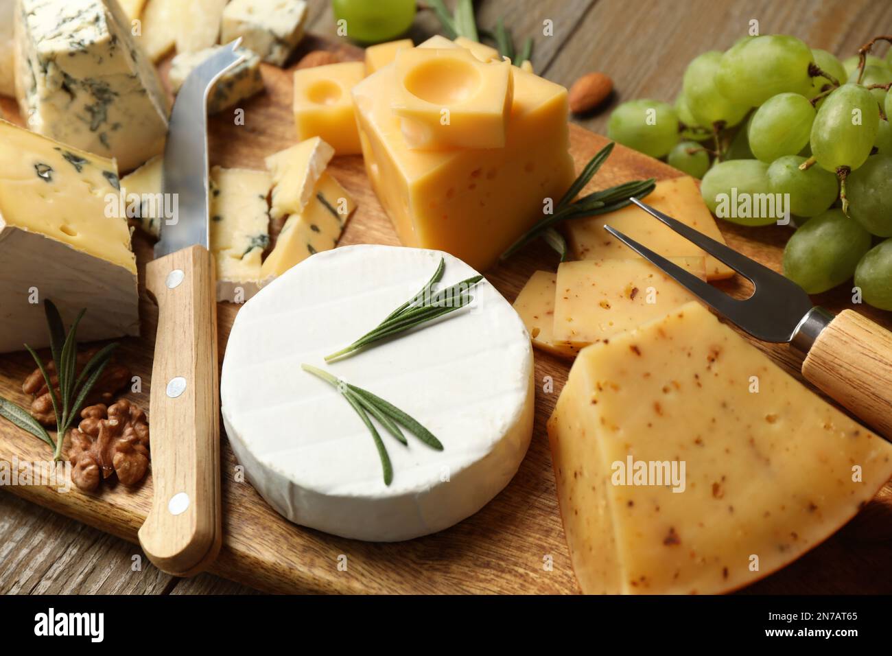 Plateau de fromages avec couteau spécialisé et fourchette sur table en bois, gros plan Banque D'Images