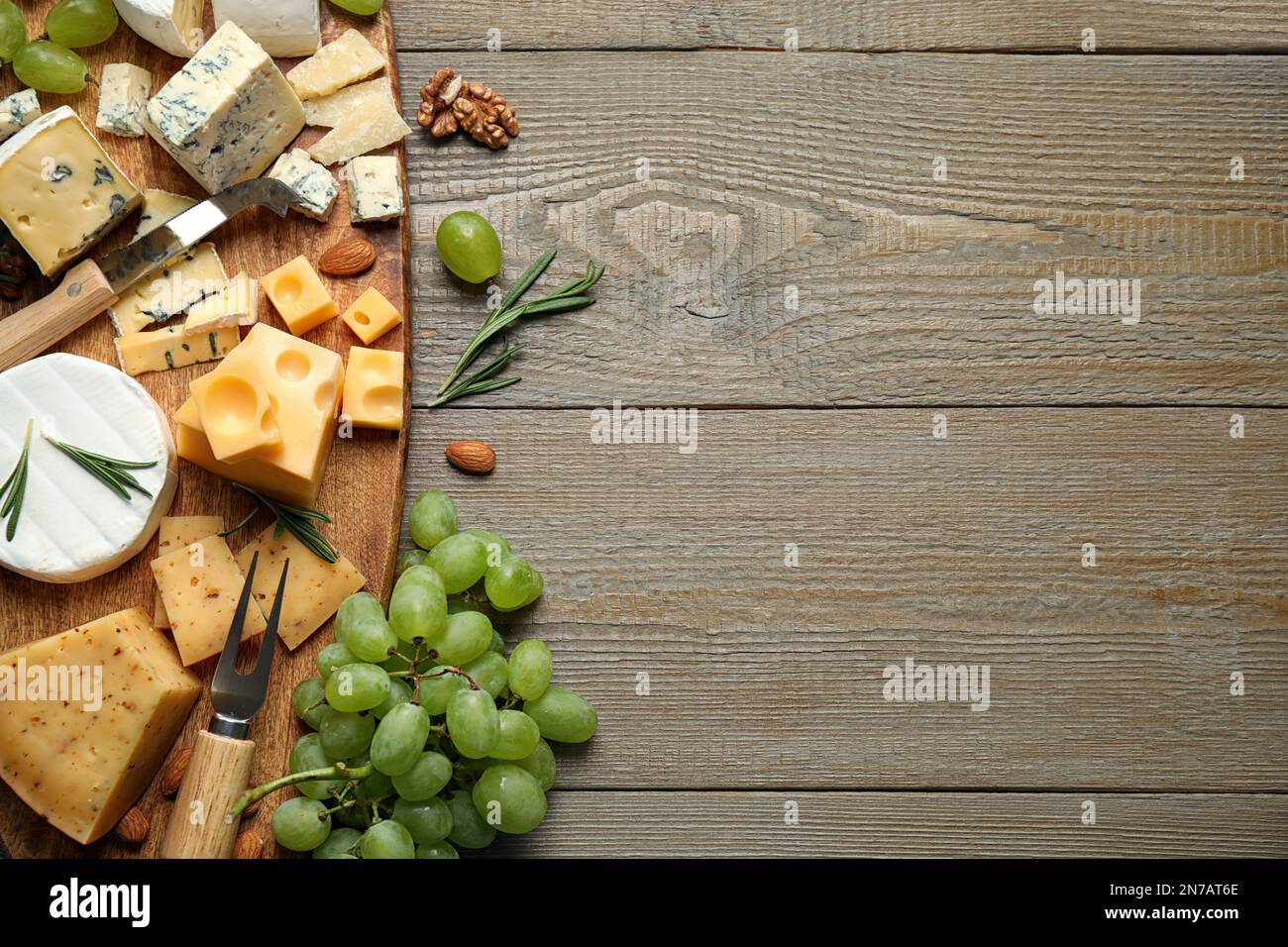 Plateau de fromages avec couteau spécialisé et fourchette sur table en bois, plat. Espace pour le texte Banque D'Images
