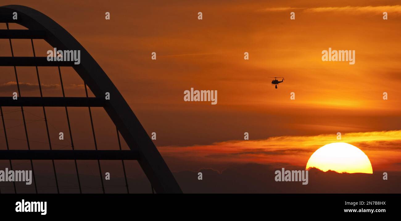 A helicopter transports sandbags to a flooded area by river Elbe besides a bridge during the sunset near Fischbeck, central Germany, Monday, June 10, 2013. Weeks of heavy rain this spring have sent the Elbe, the Danube and other rivers such as the Vltava and the Saale overflowing their banks, causing extensive damage in central and southern Germany, the Czech Republic, Austria, Slovakia and Hungary. (AP Photo/Jens Meyer) Banque D'Images