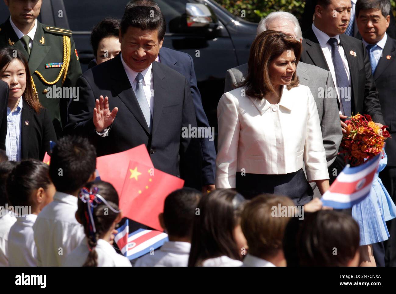 China's President Xi Jinping waves to children as he is escorted by Costa Rica's President Laura Chinchilla, right, during a welcome ceremony at the presidential house in San Jose, Costa Rica, Monday, June 3, 2013. Trinidad, a leading supplier of natural gas, was the first stop of a four-country trip in the region for Xi. After Costa Rica, he has planned stops in Mexico and the United States. (AP Photo/Arnulfo Franco) Banque D'Images