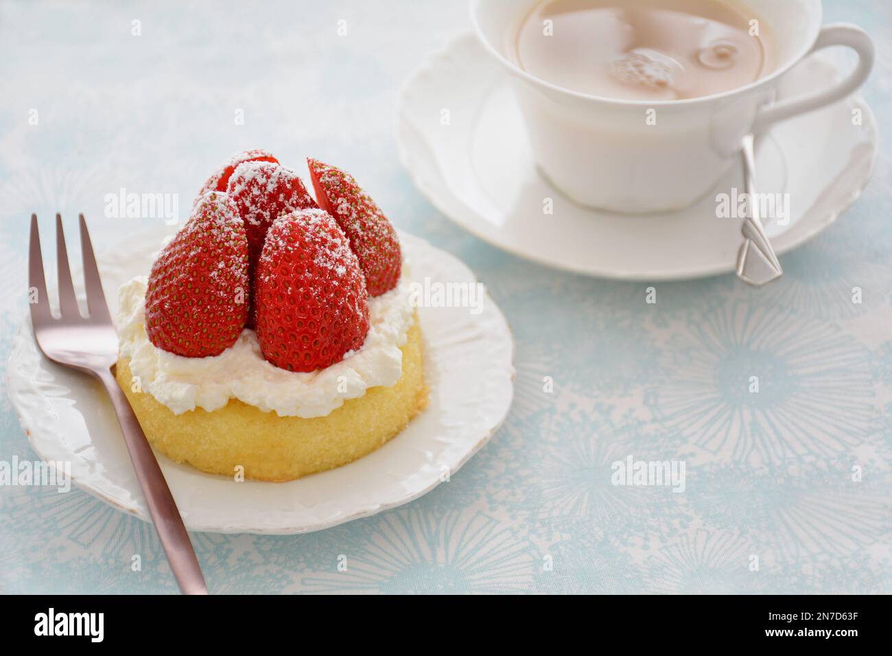 Fraises douces fraîches avec crème fouettée sur une tasse de dessert éponge jaune et une tasse de thé de format horizontal. Banque D'Images