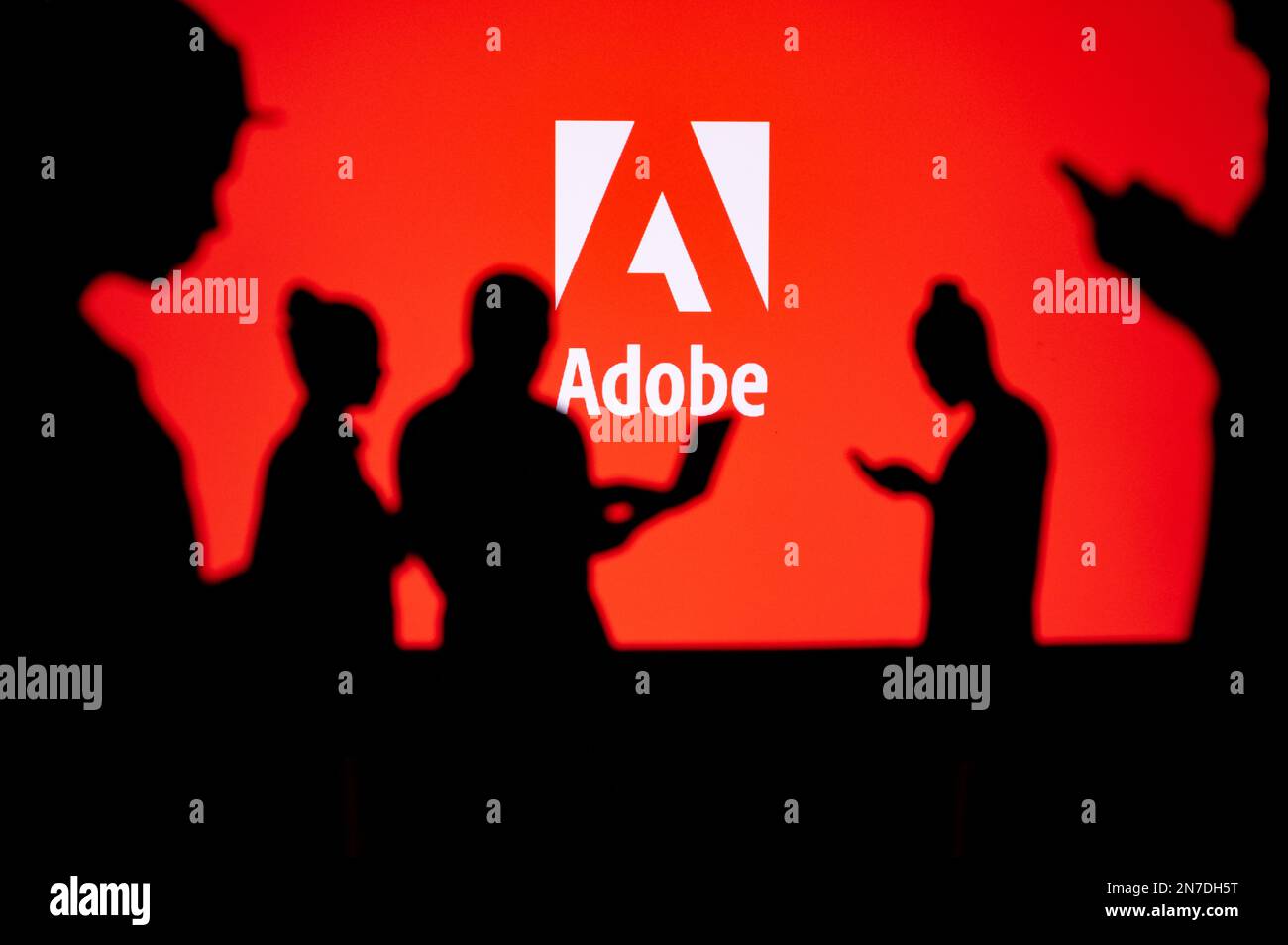 JAPON, TOKYO. 30 JANVIER 2023 : Adobe. Collaborer pour l'innovation : les développeurs Web silhouettés en action avec le logo de la société en arrière-plan Banque D'Images