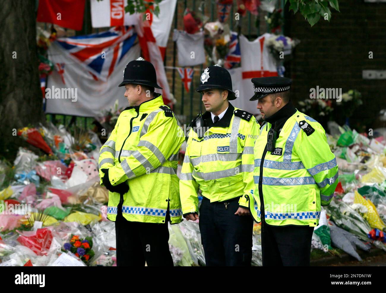 Police officers stand guard near some of the thousands of floral and other tributes left in honour of murdered 25-year-old soldier of the Royal Regiment of Fusiliers, Lee Rigby, at the scene near Woolwich Barracks in London, Tuesday, May 28, 2013 . Two men attacked and killed the soldier in broad daylight Wednesday May 22. Thousands of floral tributes have been left by public well wishers. (AP Photo/Kirsty Wigglesworth) Banque D'Images