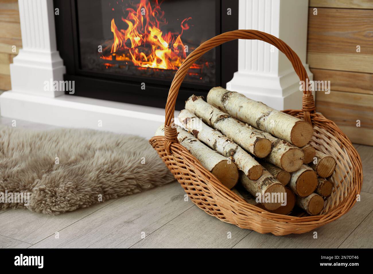 Bois de chauffage dans un panier en osier près d'une cheminée à l'intérieur  Photo Stock - Alamy