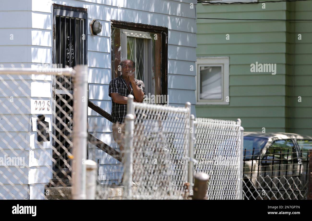 A resident looks out from his front porch across the street from the house at 2207 Seymour Street where three women were found in Cleveland, Ohio, Thursday, May 9, 2013. (AP Photo/David Duprey) Banque D'Images