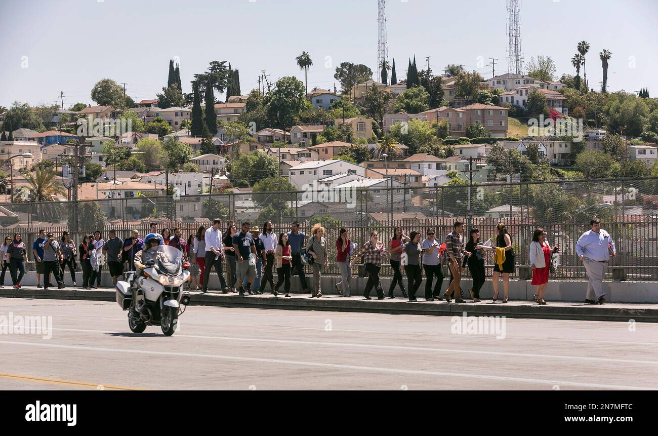 A California Highway Patrol officer escorts students back to Cal State University Los Angeles campus, after a mandatory evacuation on a report of a suspicious item, according to the Los Angeles Police Department in Los Angeles Thursday, April 18, 2013. Two telephoned bomb threats prompted officials at Cal State Los Angeles today to cancel afternoon classes and evacuate the campus. (AP Photo/Damian Dovarganes) Banque D'Images