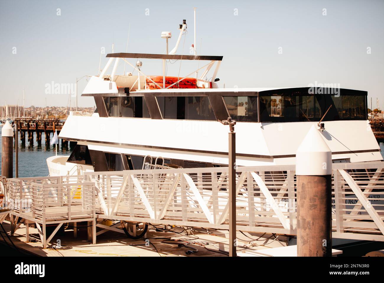 Gros plan sur un bateau de croisière blanc stationné à matina, ville avec vue sur la baie et petits bateaux de croisière Banque D'Images