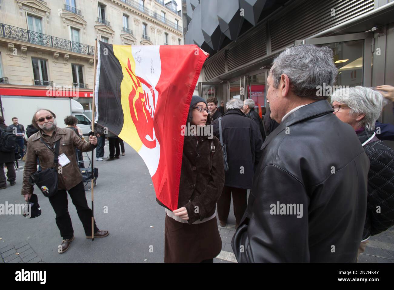 Supporters of the Indian cause hold a flag of the American Indian Movement stand outside of the Druout's auction house to protest the auction of Native American Hopi tribe masks in Paris, Friday, April 12, 2013. A contested auction of dozens of Native American tribal masks went ahead Friday afternoon following a Paris court ruling, in spite of appeals for a delay by the Hopi tribe, its supporters including actor Robert Redford, and the U.S. government. (AP Photo/Michel Euler) Banque D'Images