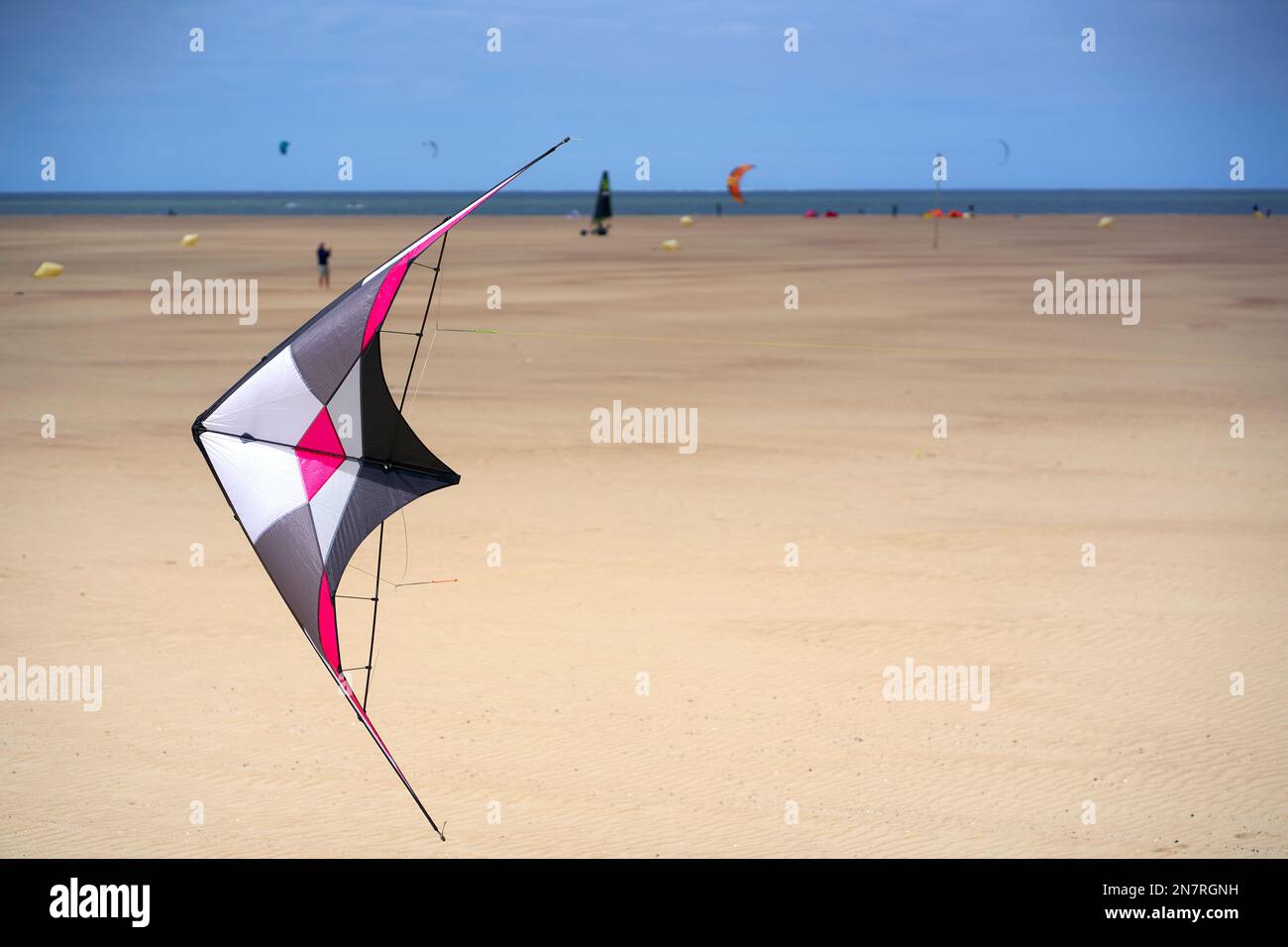 Gros plan de cerf-volant coloré (Stabdrachen) sur une plage de sable animée en Hollande. Jouet pour les jours venteux. Sportifs de loisirs sur la mer. Banque D'Images