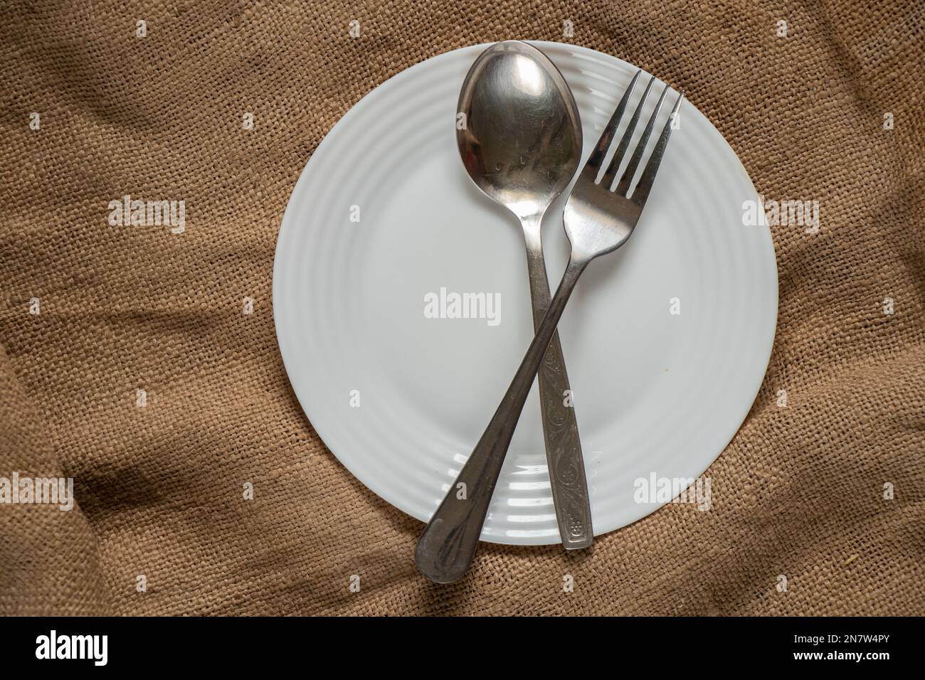 la fourchette de la cuillère repose sur une assiette blanche sur un vieux recouvrement sur la table de près Banque D'Images