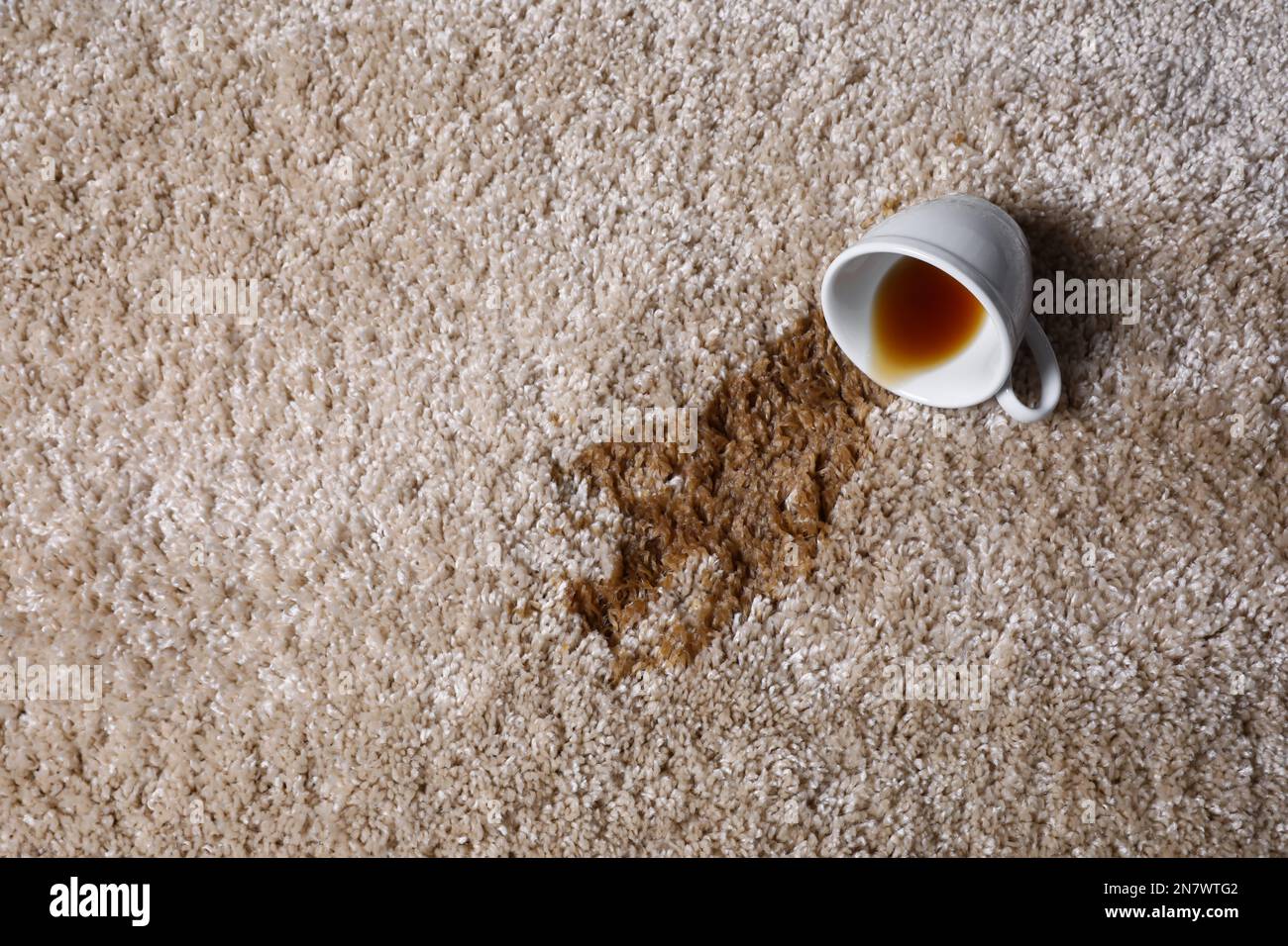 Tasse renversée et thé renversé sur la moquette beige, vue de dessus. Espace pour le texte Banque D'Images Tasse renversée et thé renversé sur la moquette beige, vue de dessus. Espace pour le texte Banque D'Images