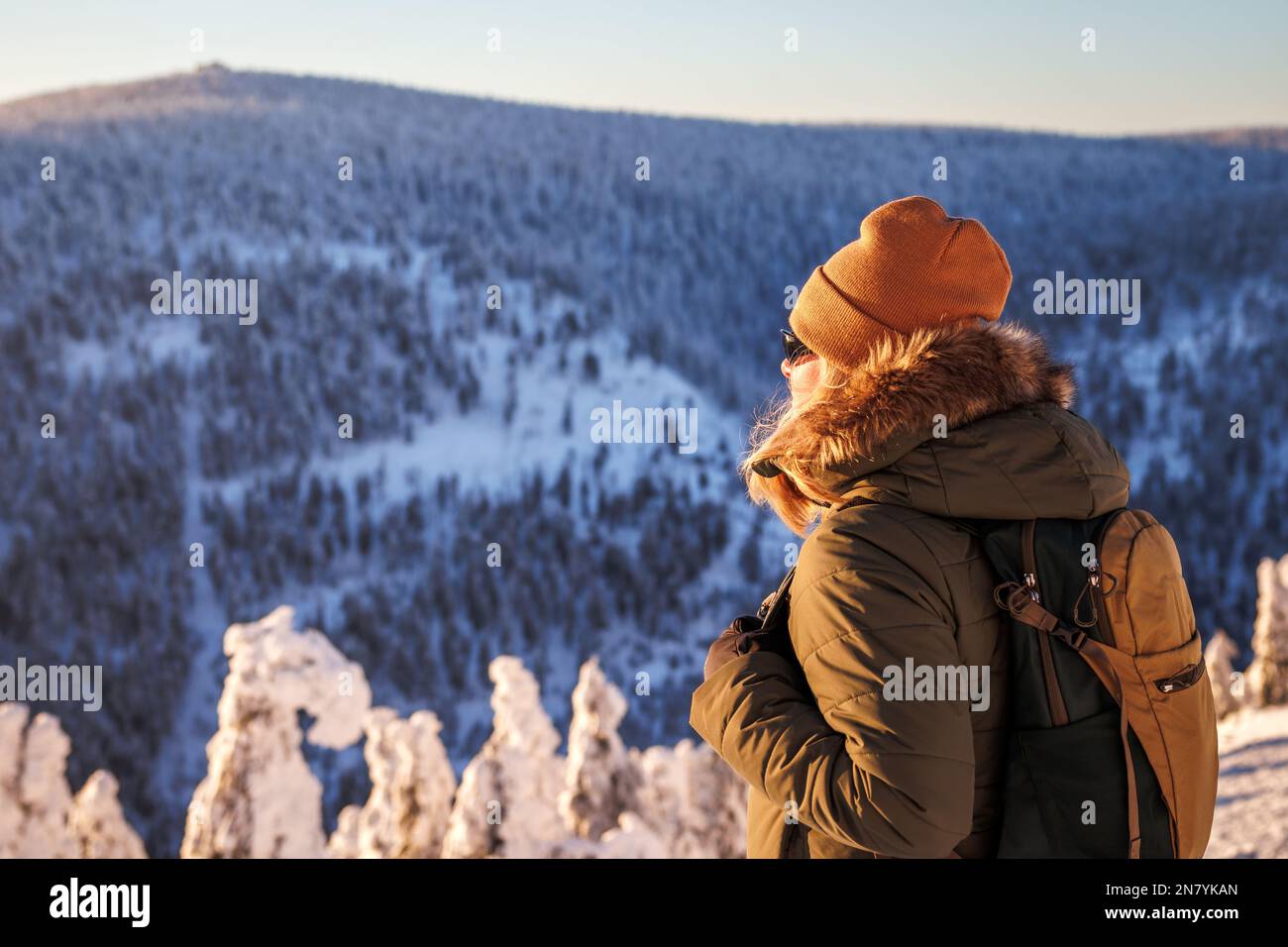 Femme regardant les montagnes depuis le point de vue pendant la randonnée en hiver. Randonneur féminin avec sac à dos portant une veste et un chapeau en tricot Banque D'Images